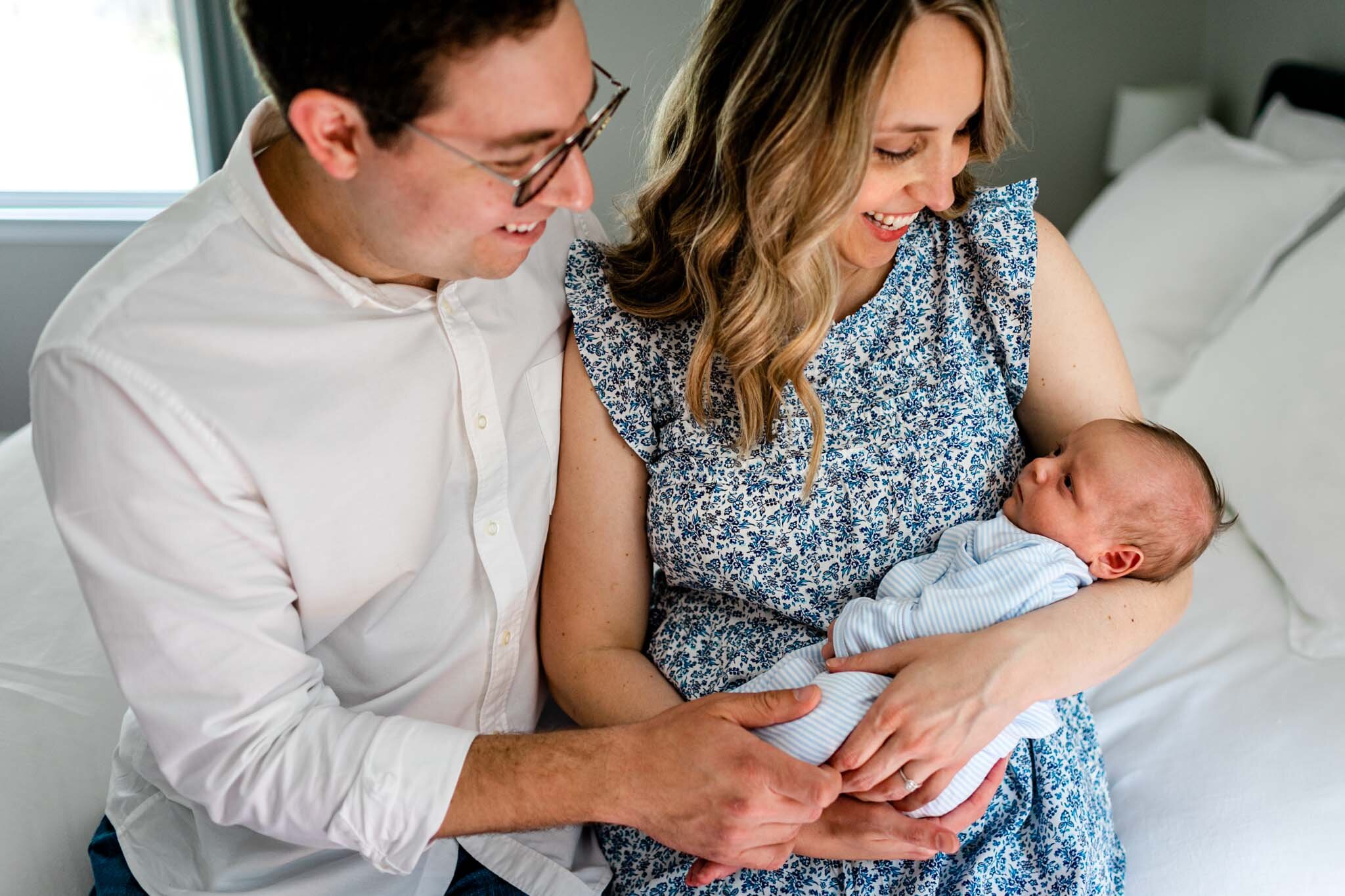 Couple sitting on bed holding baby boy | Greensboro Newborn Photographer | By G. Lin Photography