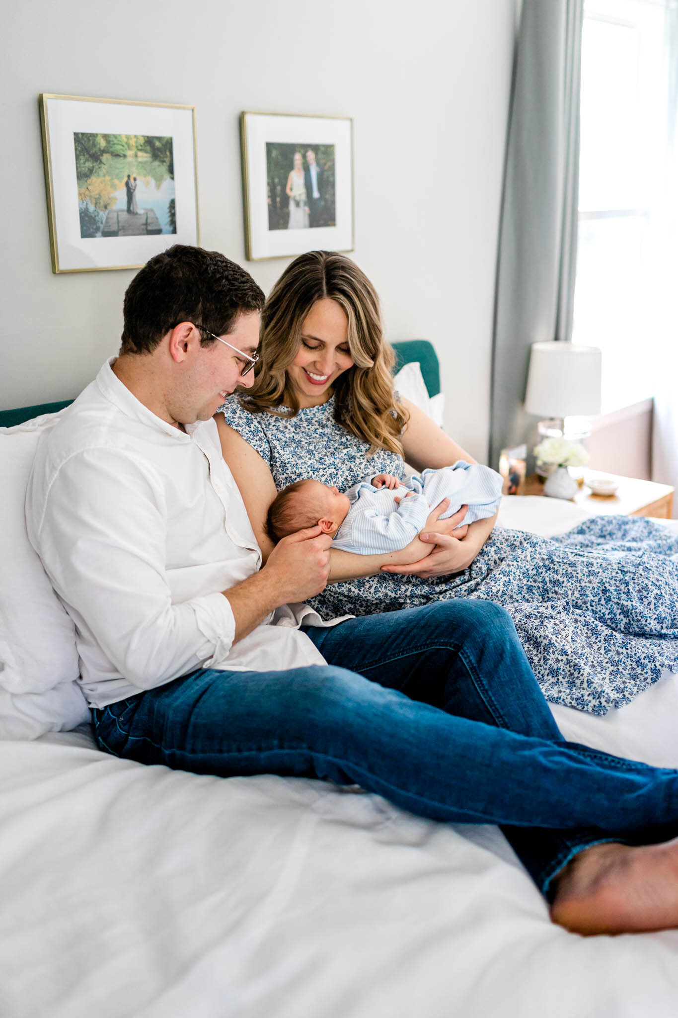 Couple sitting on bed with newborn baby | Greensboro Newborn Photographer | By G. Lin Photography