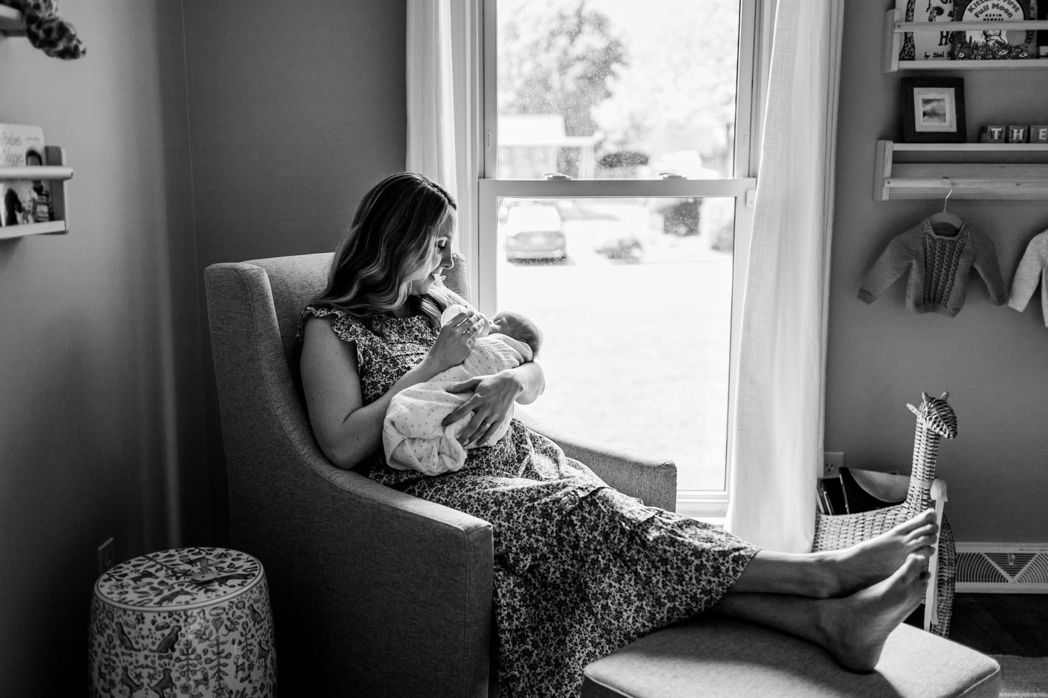 Black and white photo of mother holding baby next to window | Greensboro Newborn Photographer | By G. Lin Photography