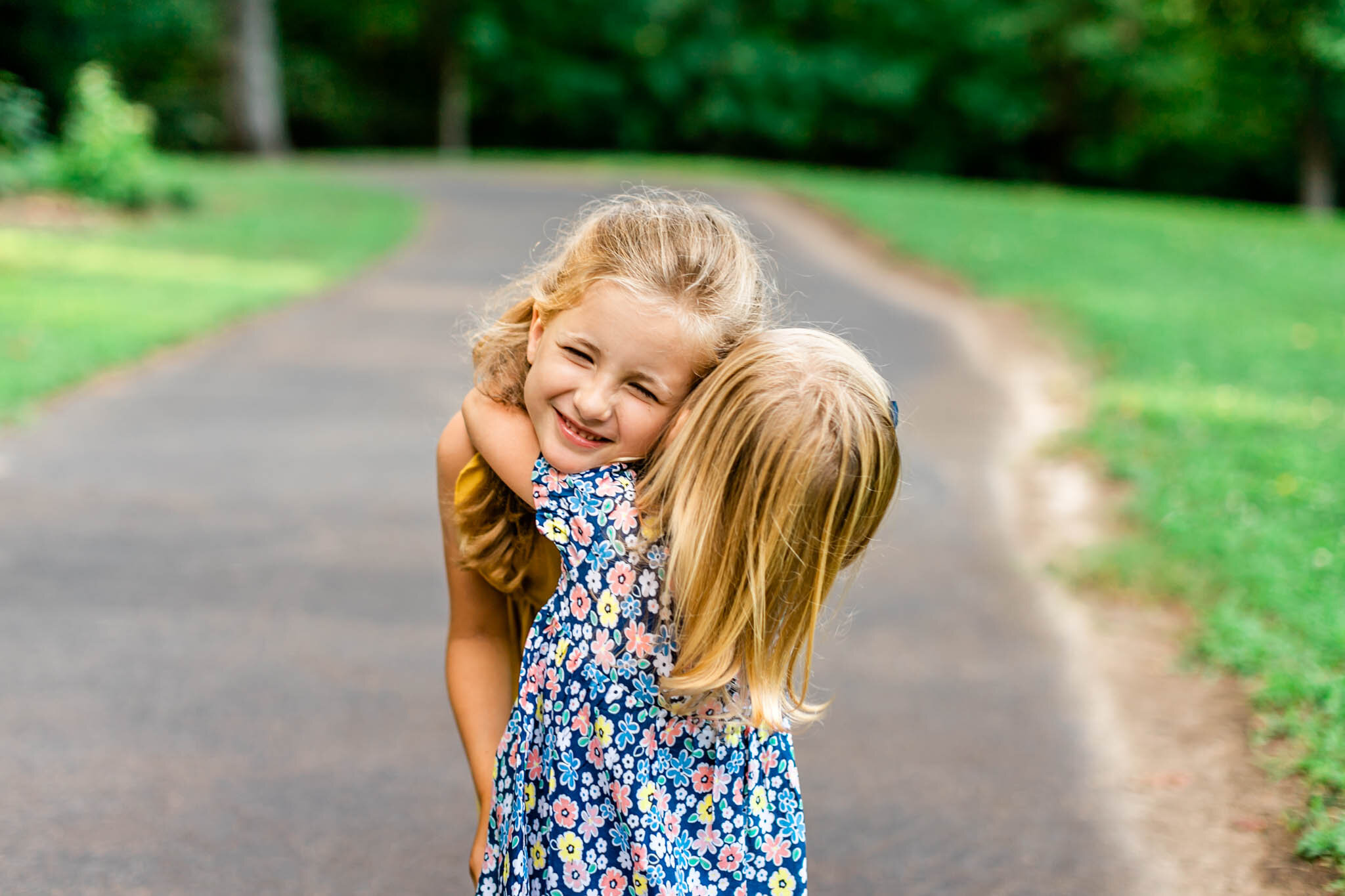 Two sisters hugging one another outside | Cary Family Photographer | By G. Lin Photography