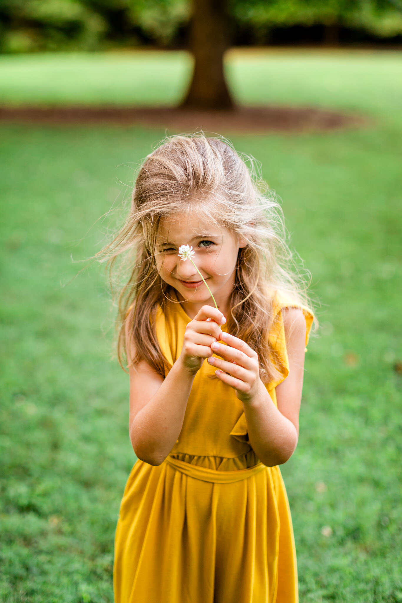 Girl in yellow dress holding up flower | Cary Family Photographer | By G. Lin Photography