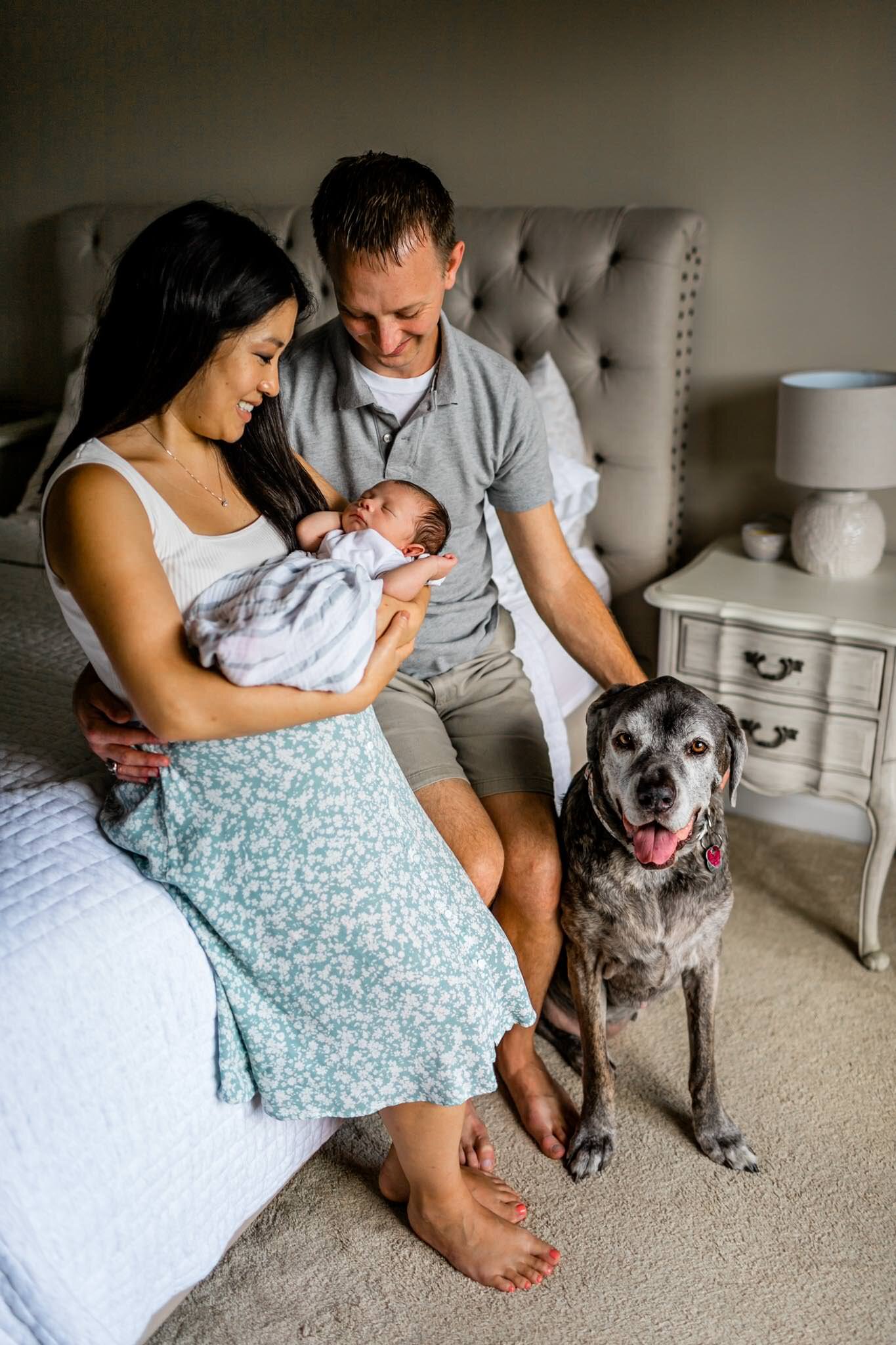 Family sitting on bed and smiling with newborn baby | Durham Newborn Photographer | By G. Lin Photography