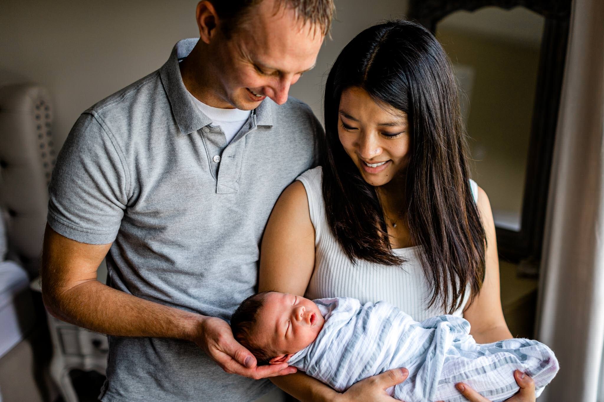Father and mother holding baby in bedroom | Durham Newborn Photographer | By G. Lin Photography | Lifestyle newborn photography at home