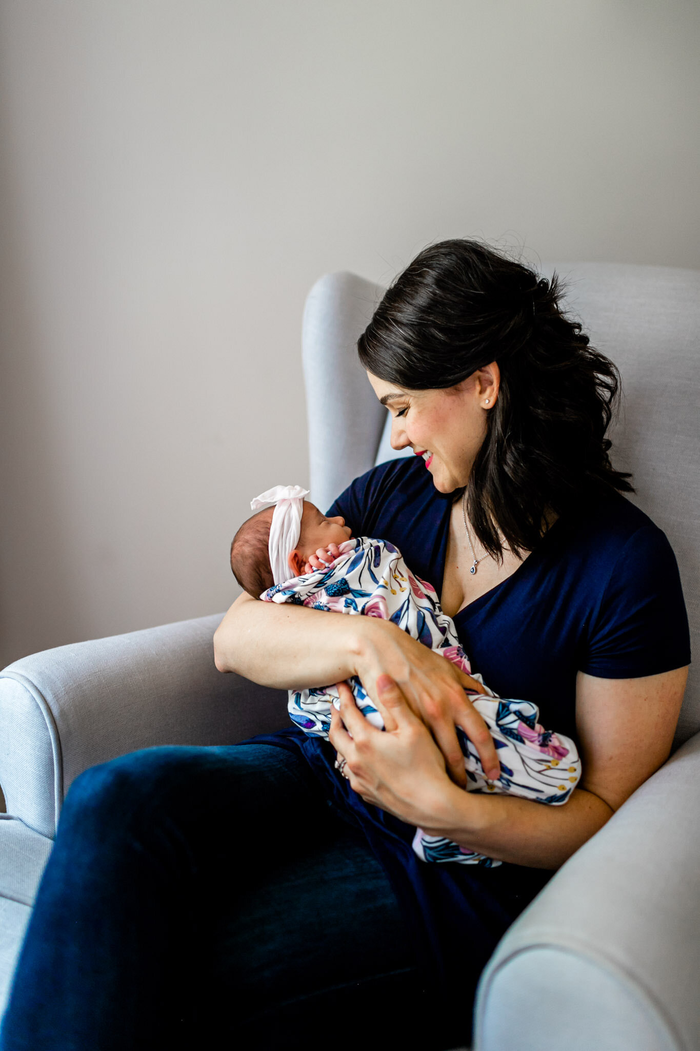 Durham Newborn Photographer | By G. Lin Photography | Mother holding baby by window and sitting in chair