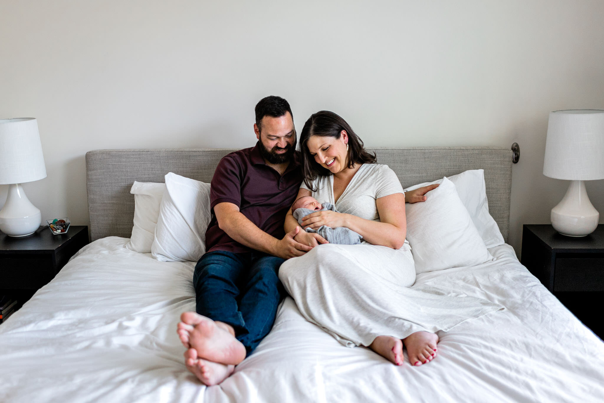 Beautiful lifestyle photo of parents sitting on bed with baby | Durham Newborn Photographer | By G. Lin Photography