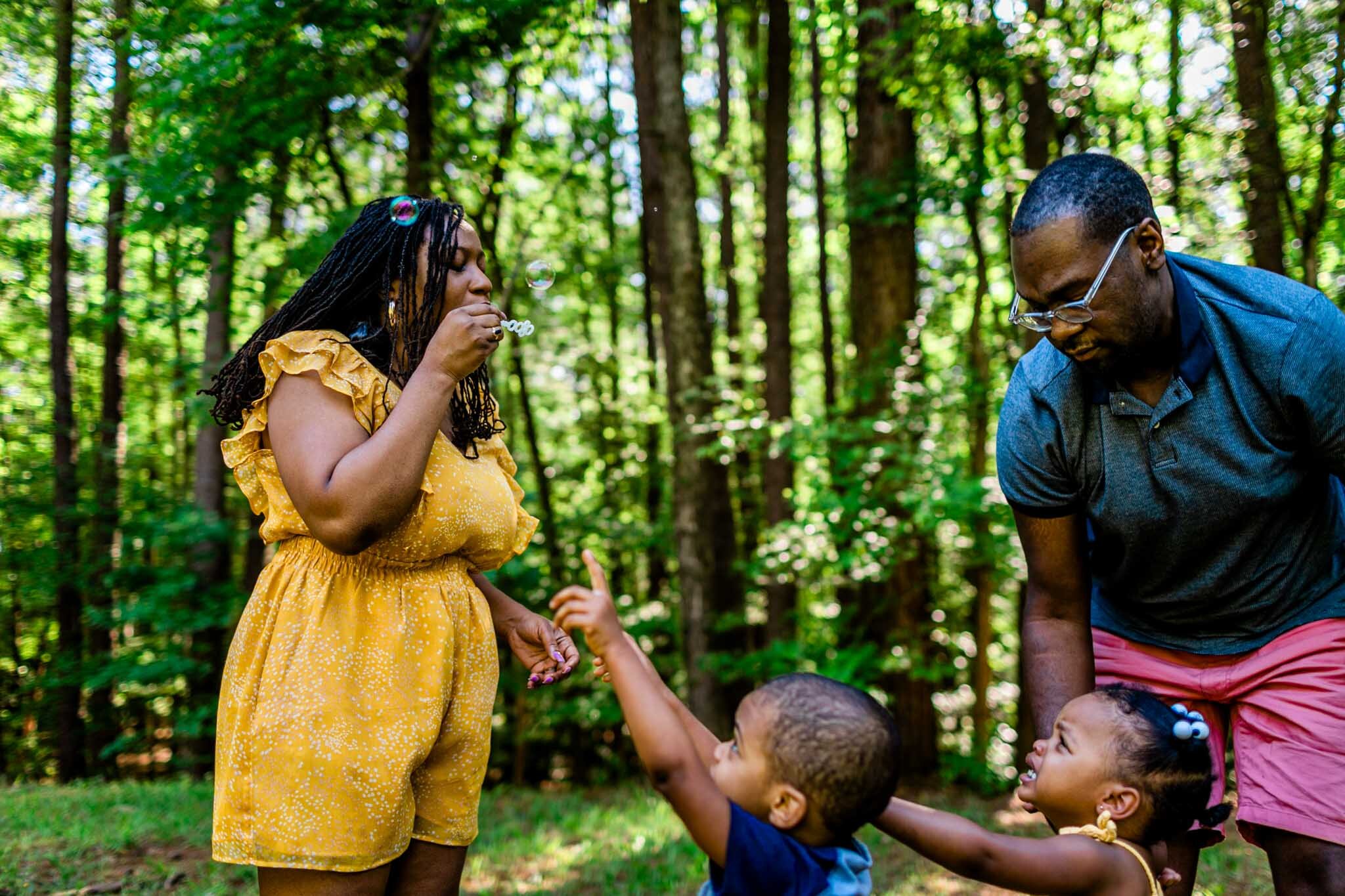 Mother in yellow dress blowing bubbles | Raleigh Family Photographer | By G. Lin Photography | Umstead Park