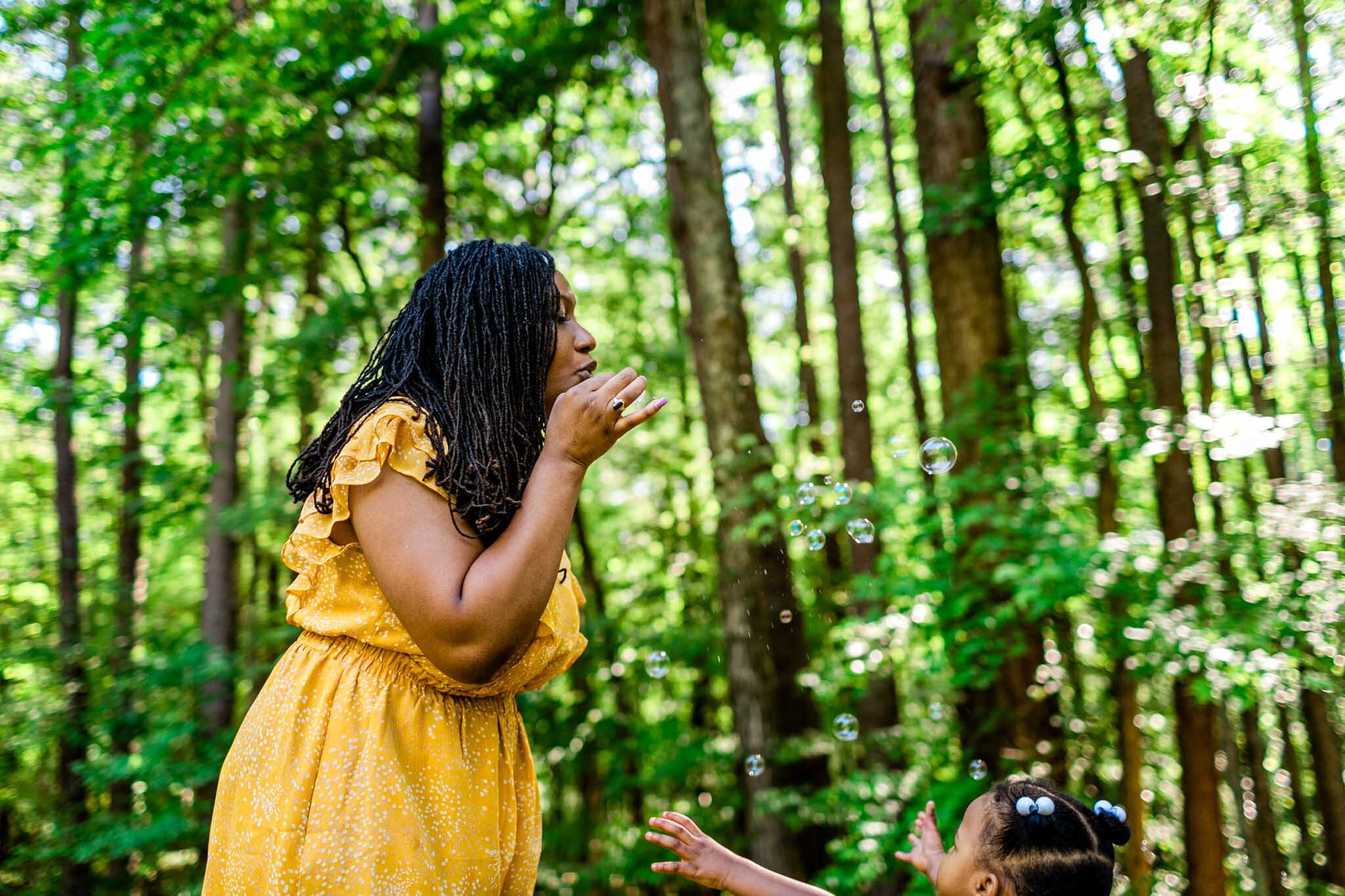 Raleigh Family Photographer | By G. Lin Photography | Umstead Park | Mother blowing bubbles for kids