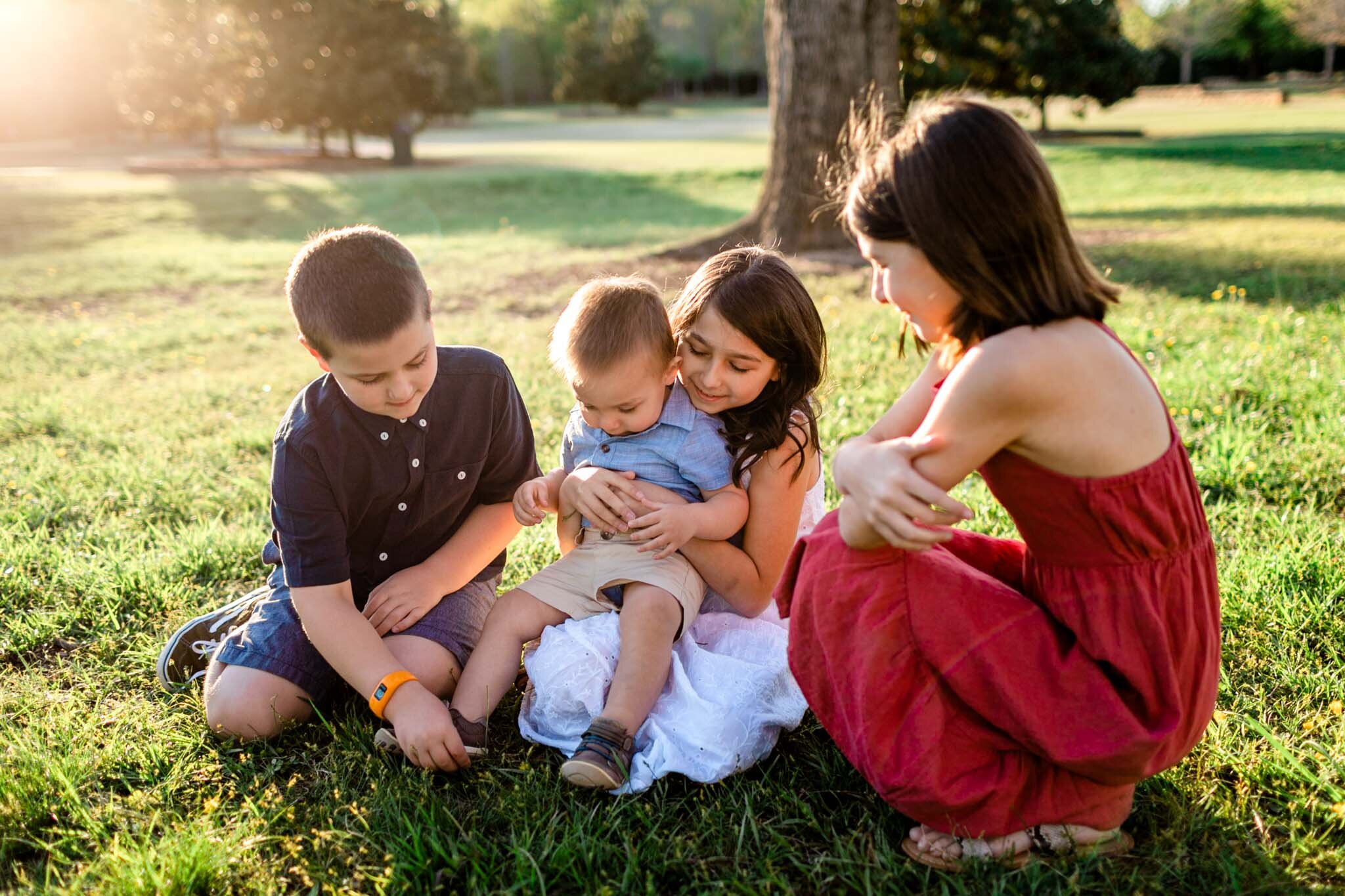 Raleigh Family Photographer | Joyner Park | By G. Lin Photography | Four children sitting on grass with sunset
