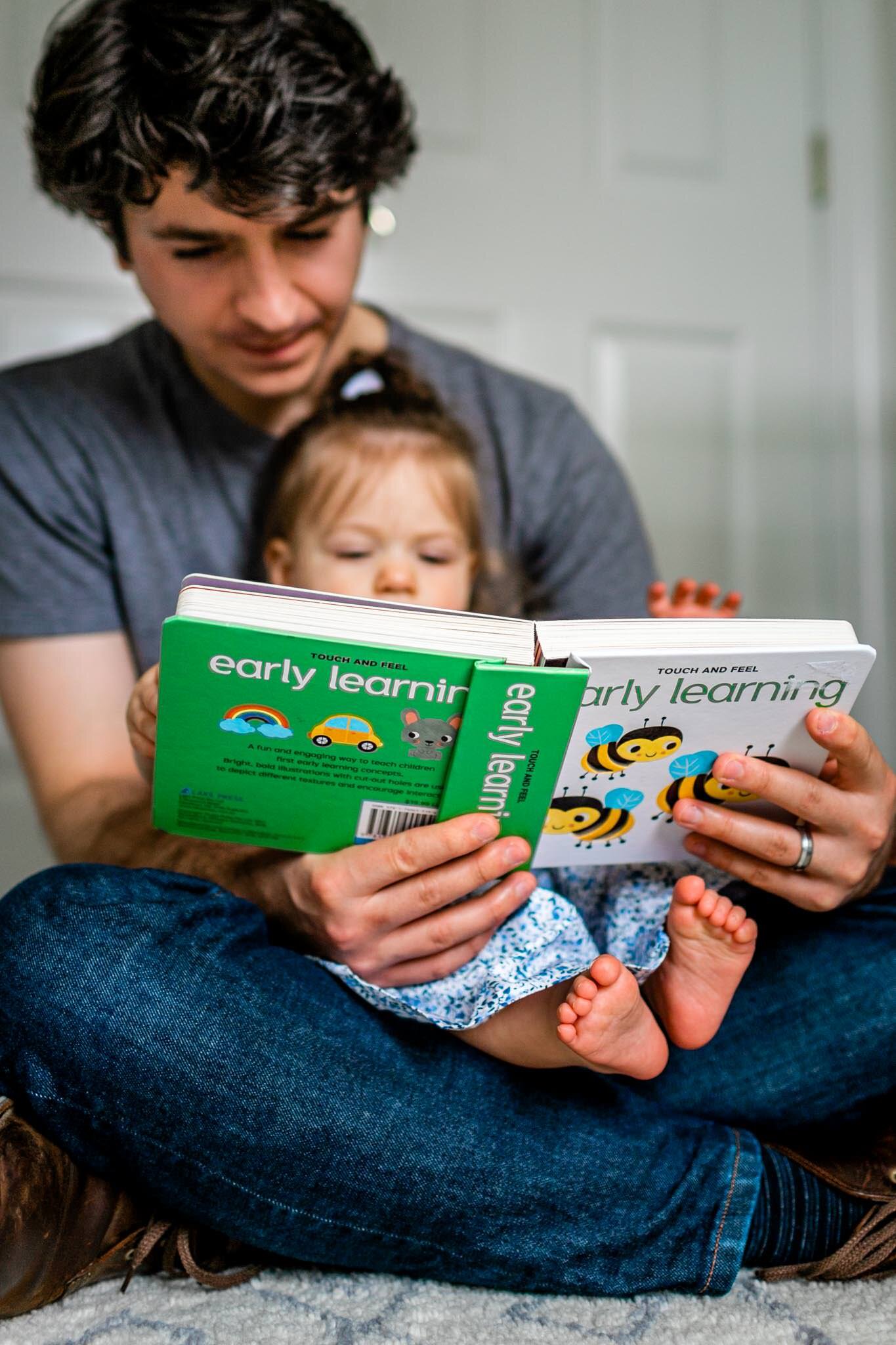 Baby girl sitting on dad's lap reading | Durham Family Photographer | By G. Lin Photography 