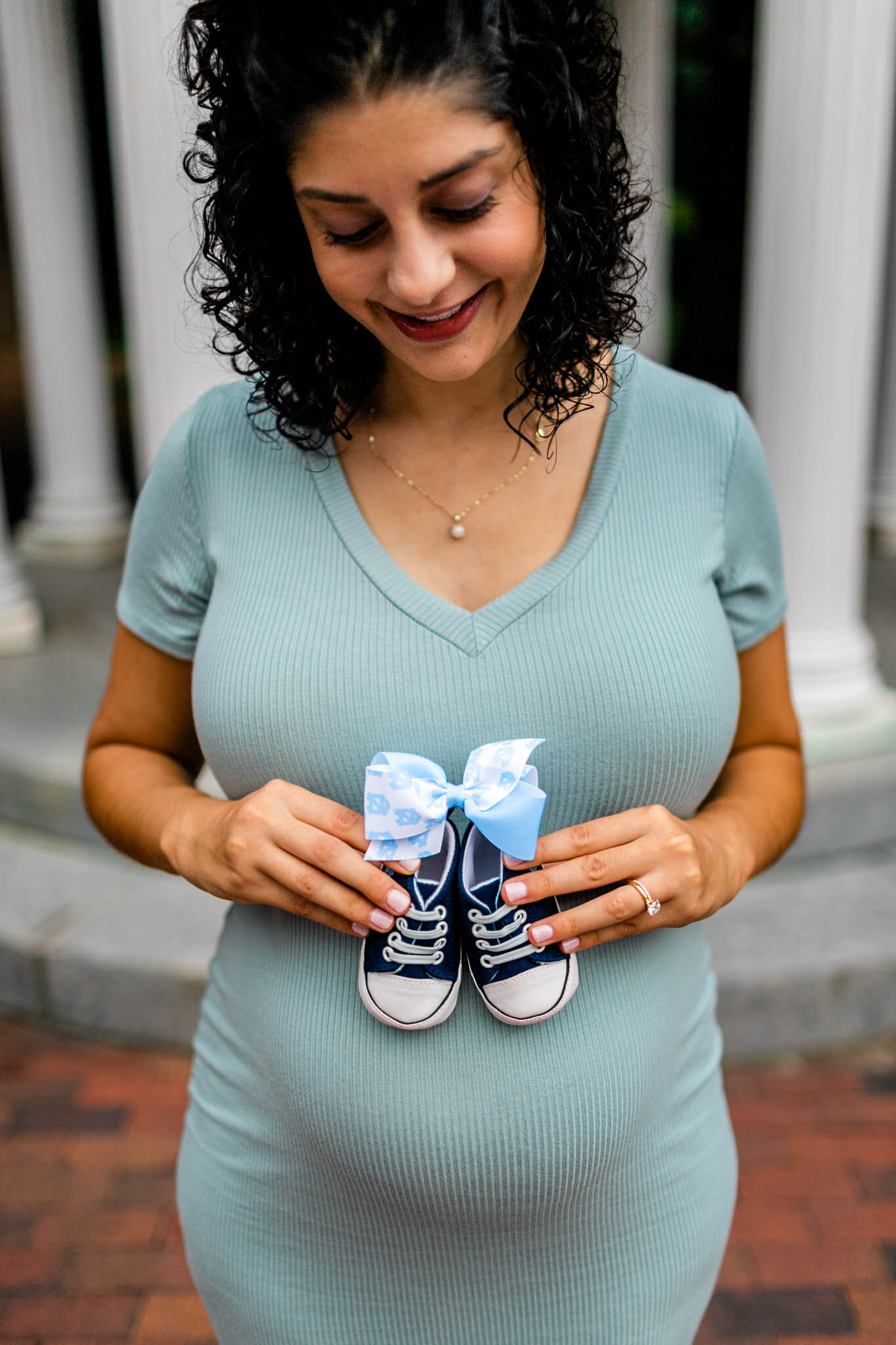 UNC Chapel Hill Maternity Photography | By G. Lin Photography | Woman holding baby shoes at the Old Well