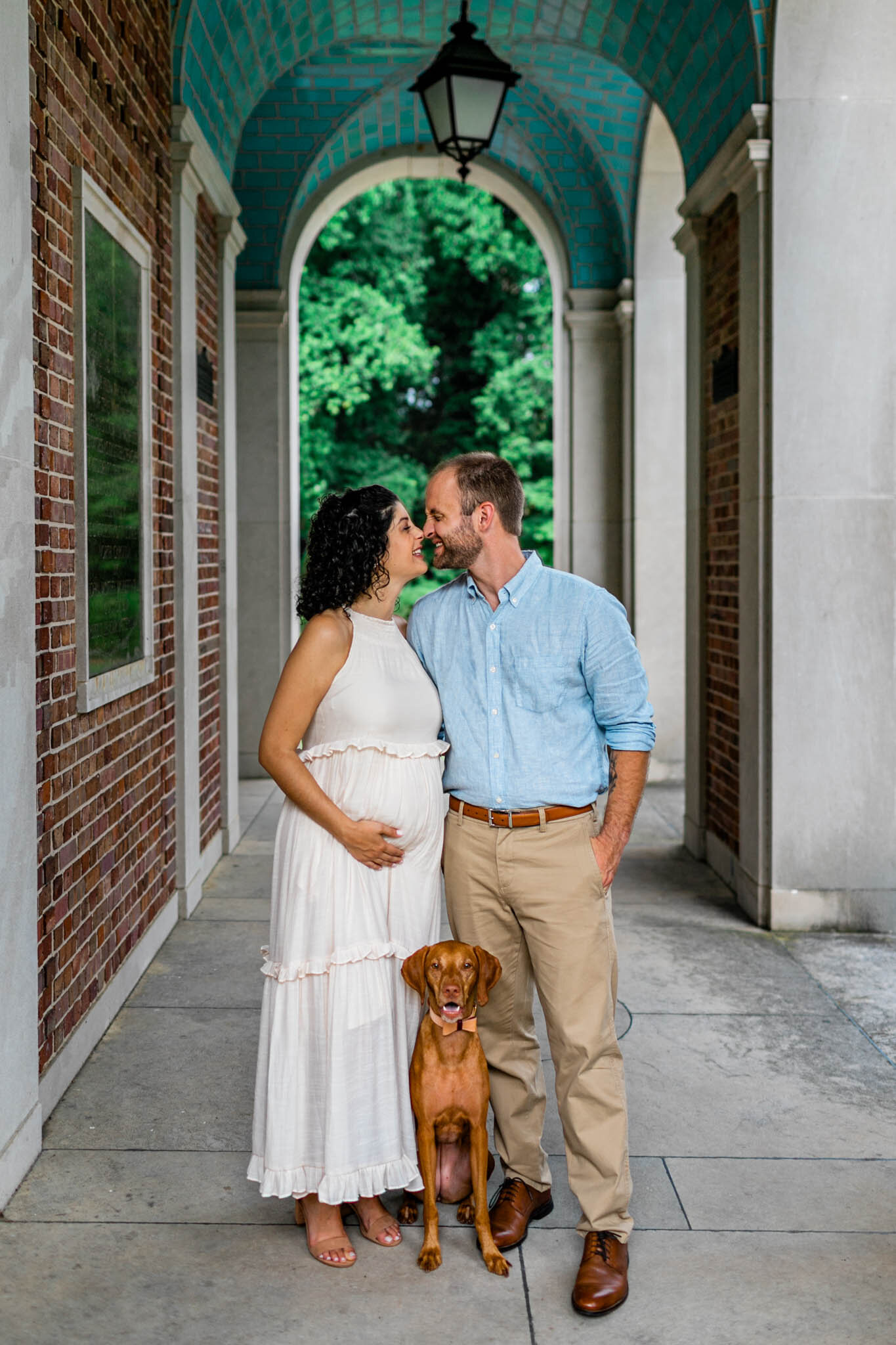 UNC Chapel Hill Maternity Photography | By G. Lin Photography | Man and woman laughing with dog and standing under the Bell Tower