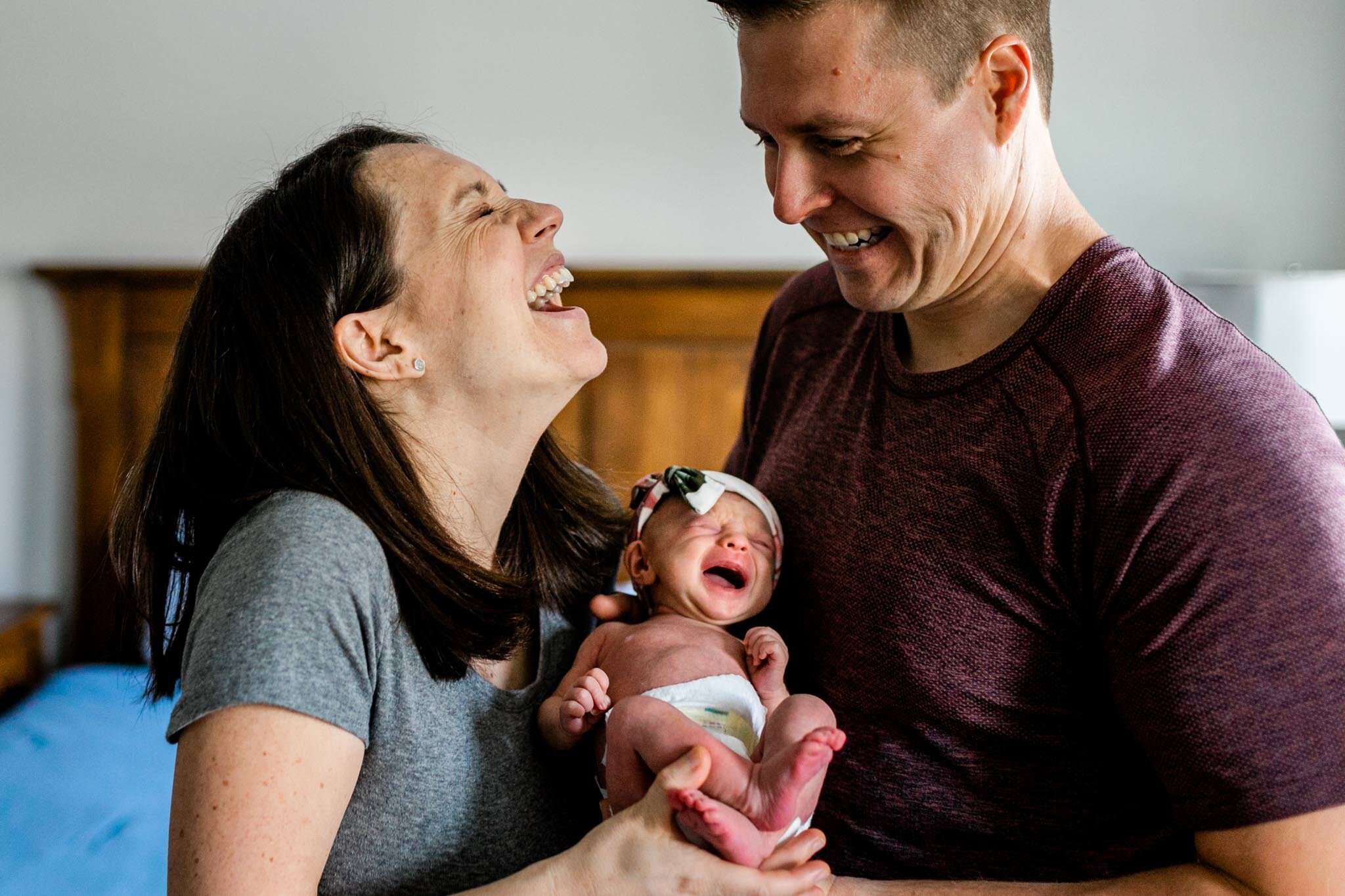 Hillsborough Newborn Photographer | By G. Lin Photography | Mother and father laughing while holding baby crying