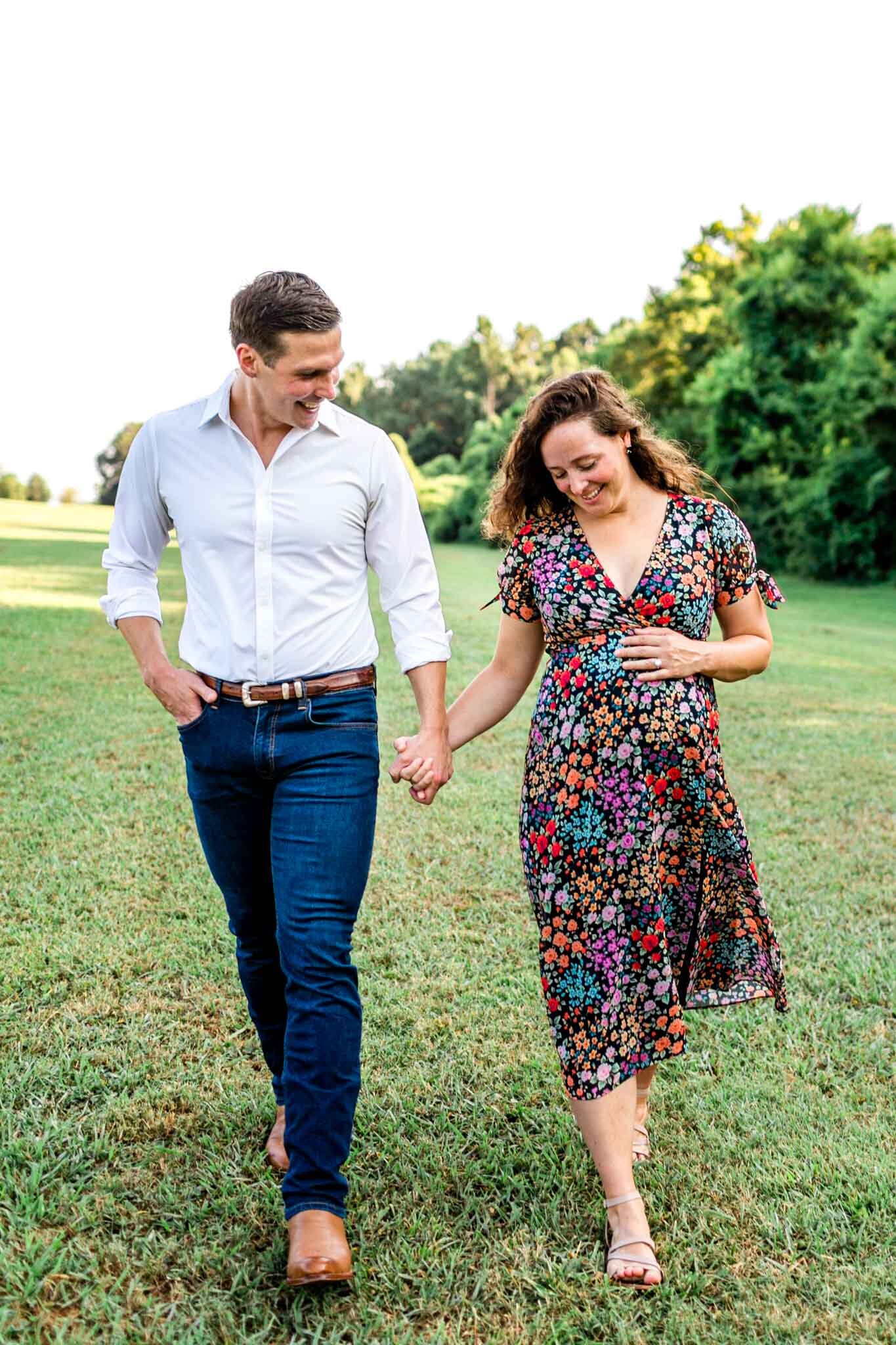 Raleigh Maternity Photographer | Dix Park | By G. Lin Photography | Man and woman holding hands and looking at baby bump