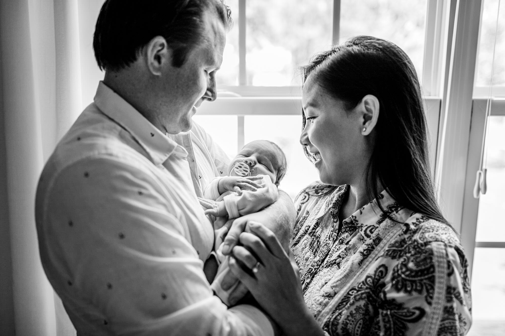 Pittsboro Newborn Photographer | By G. Lin Photography | Beautiful black and white photo of parents holding baby by the window