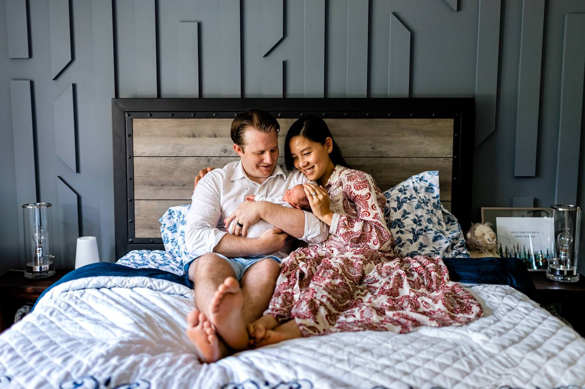 Pittsboro Newborn Photographer | By G. Lin Photography | Man and woman sitting on bed with baby
