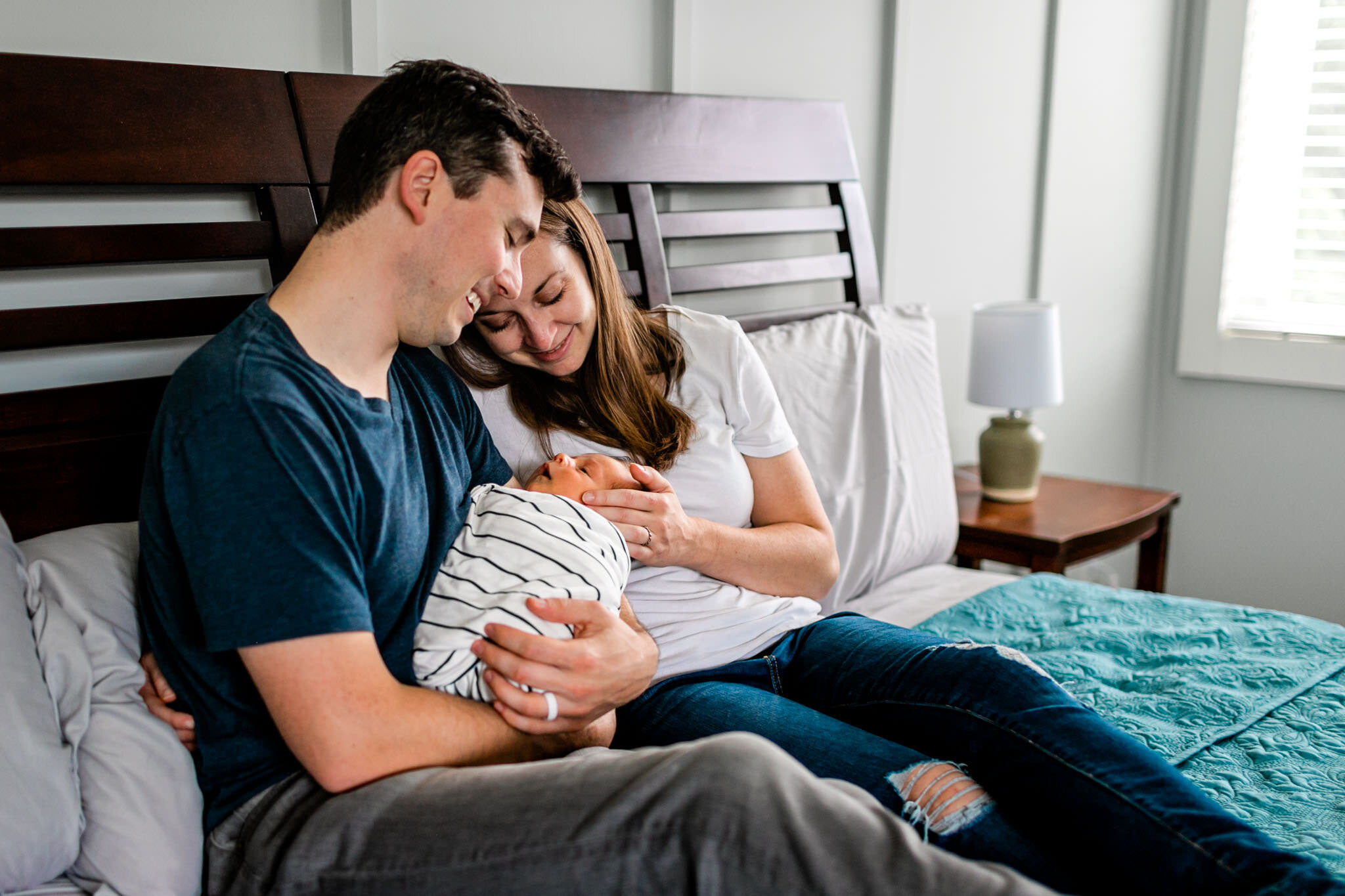 Durham Newborn Photographer | By G. Lin Photography | Parents sitting on bed with baby cuddling