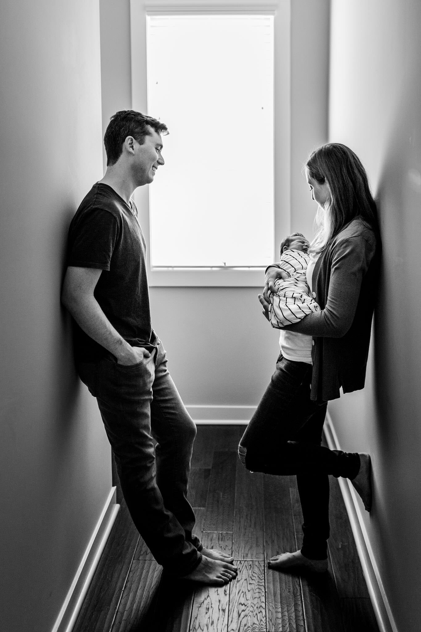 Durham Newborn Photographer | By G. Lin Photography | Black and white image of parents standing in hallway with baby