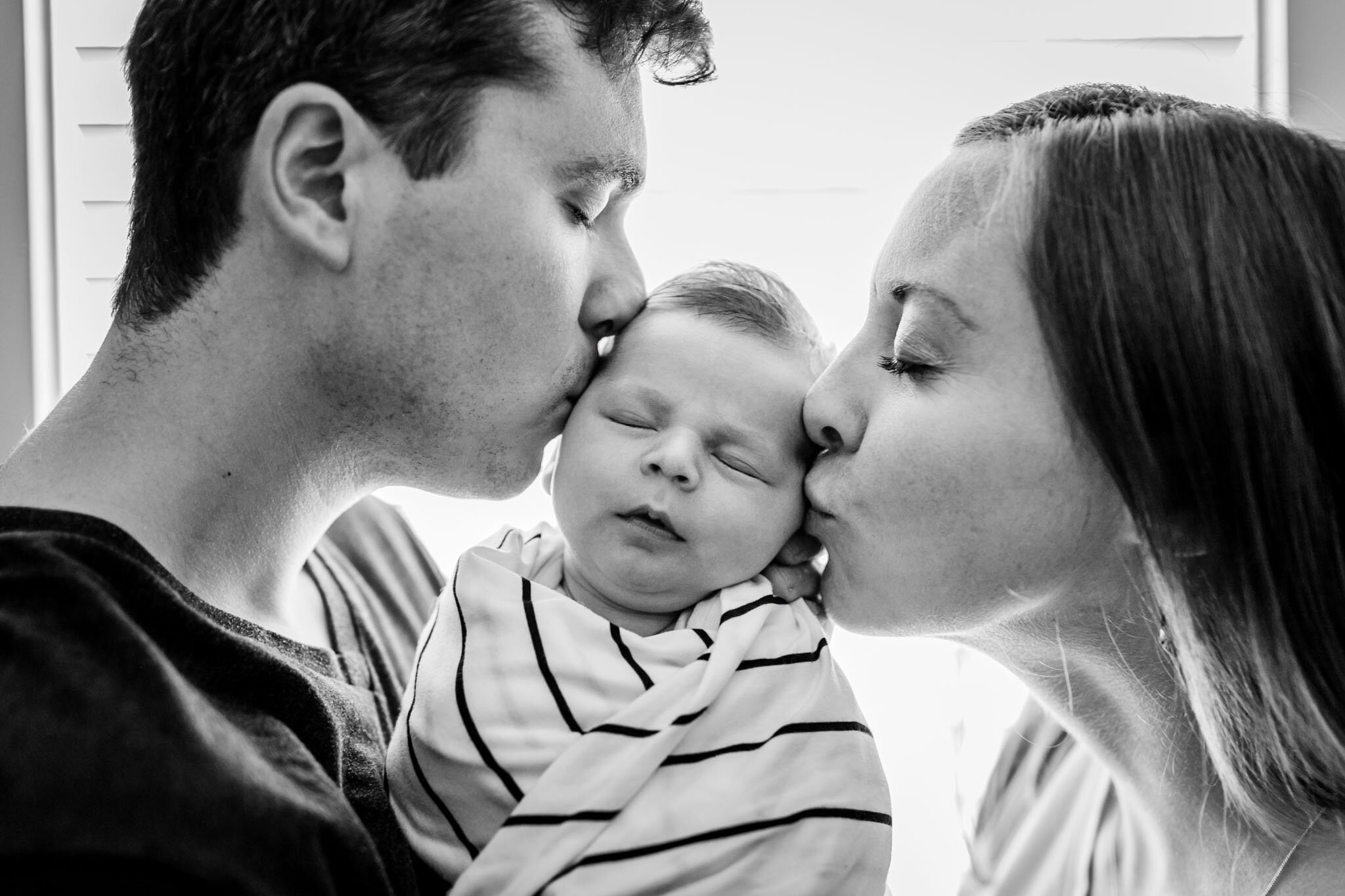 Durham Newborn Photographer | By G. Lin Photography | Man and woman kissing baby's cheeks