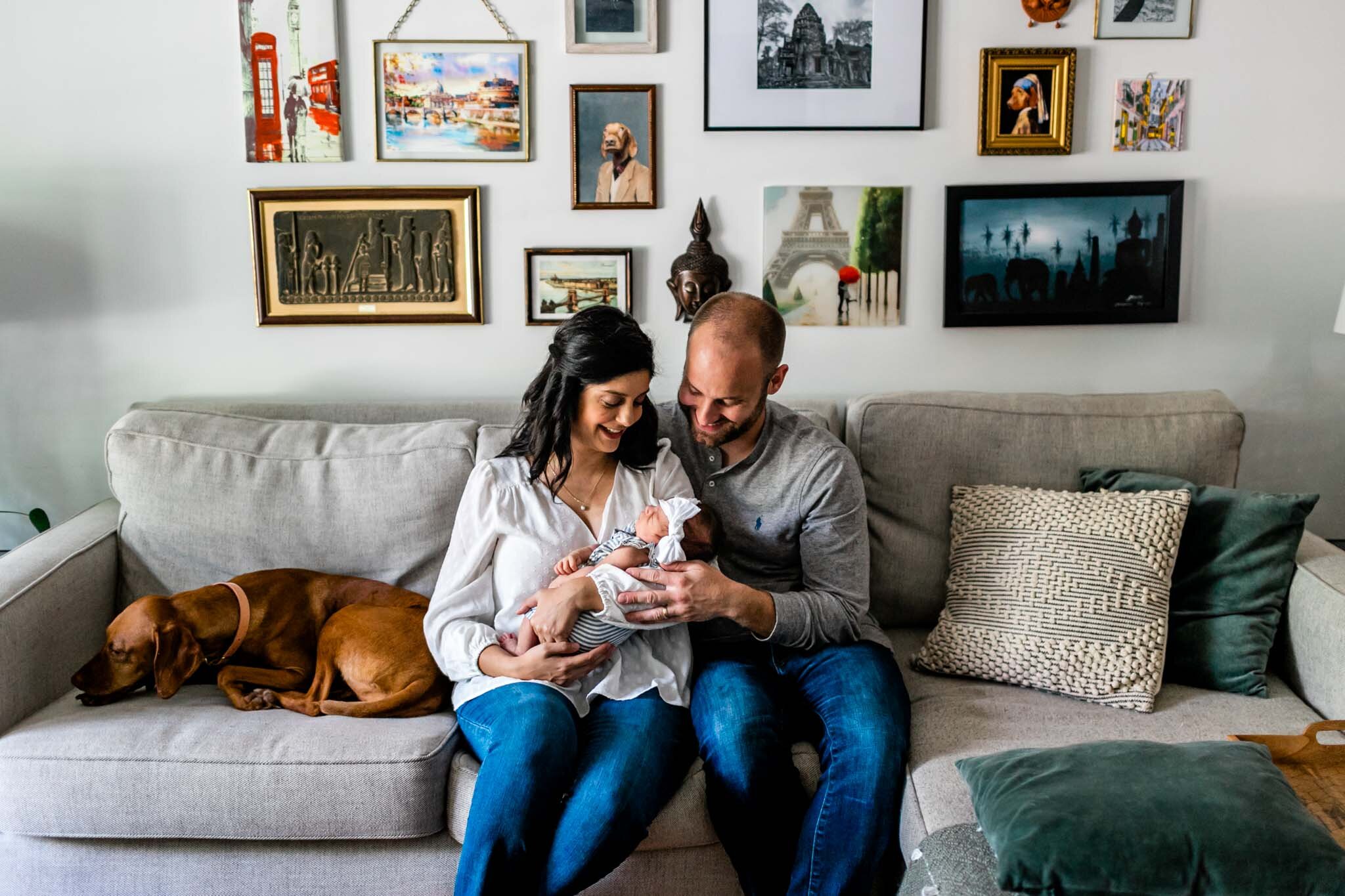 Charlotte Newborn Photographer | By G. Lin Photography | Mother and father sitting on sofa with baby and dog