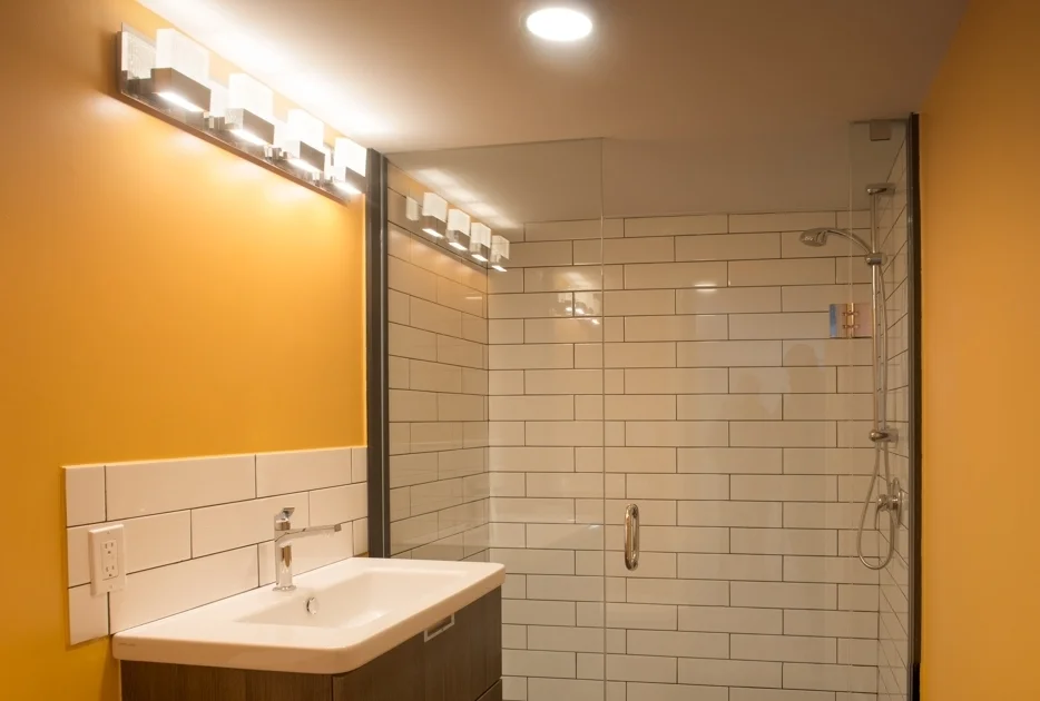 Bathroom shower with glass doors and sink, golden coloured walls
