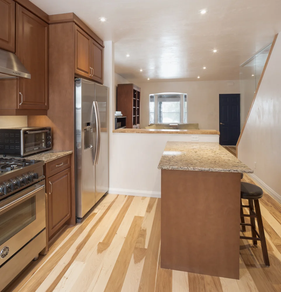 Open concept ground floor kitchen and living room. wood floor, wood cabinets, steel appliances, lime plaster walls.