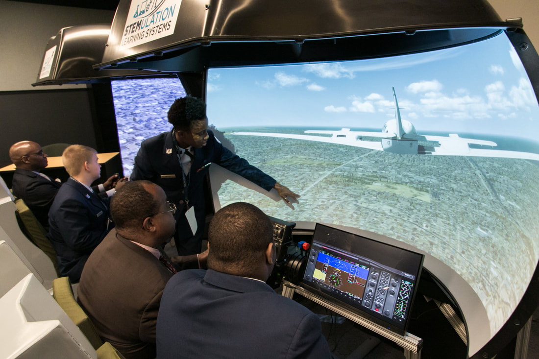 Student demonstrating flight simulator to Educators