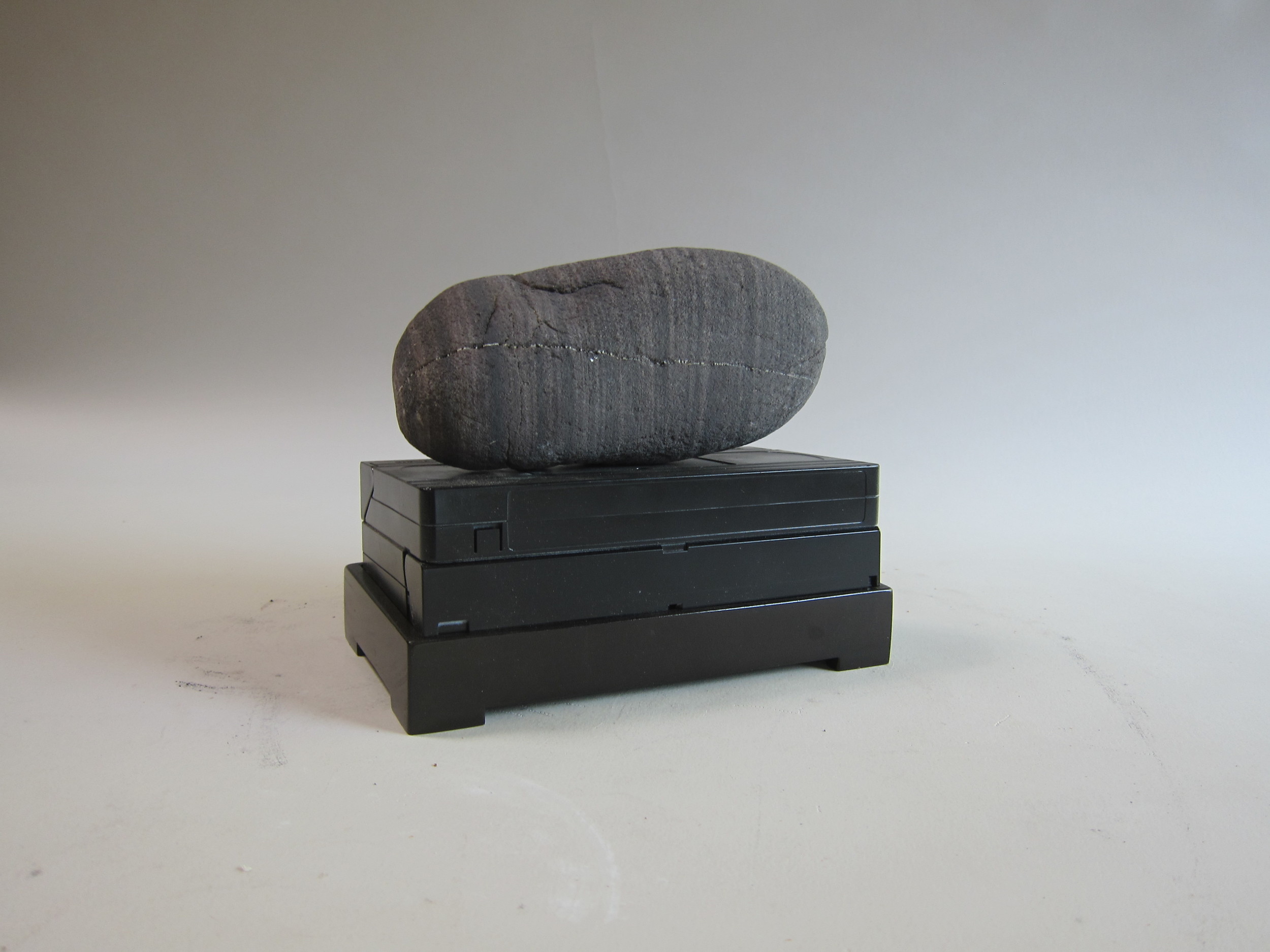   Atlantic Ocean beach stone, VCR cassette, enamel paint, wood.&nbsp;  