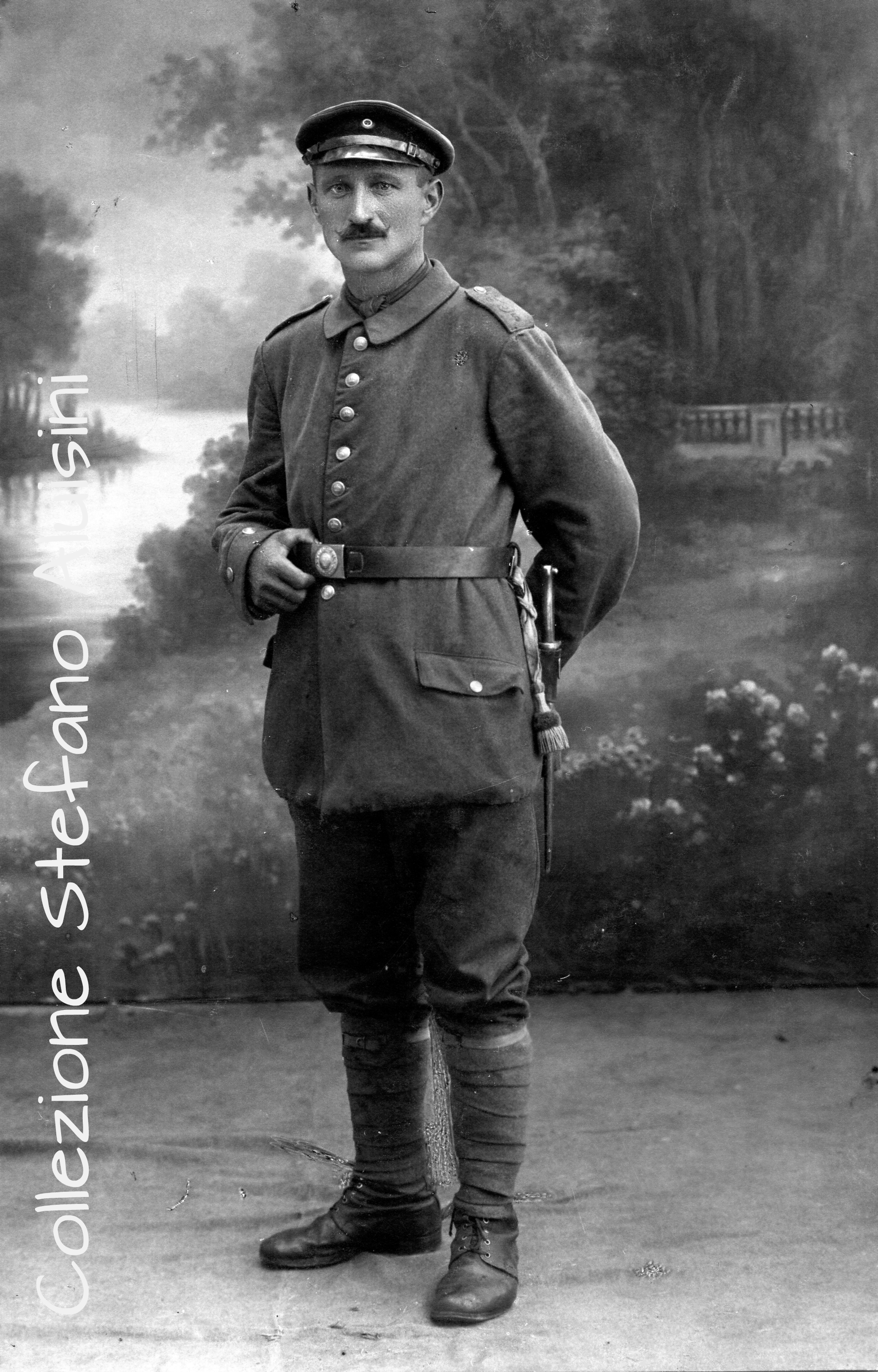 Fante della Landwehr Prussiana, riconoscibile dai bottoni con la corona e dalla fibbia con il motto “Got mit uns”. La coccarda sul berretto è teoricamente destinata ai soli sottufficiali. Indossa il berretto di servizio per truppa modello 1908 (Dienstmütze mit Schirm M. 1908). Fotografia acquistata in Francia, immagine studio Brudner - Wilno (ovvero Wilma, Vilnius oggi Lituania) – lettura dello Storico Roberto Todero