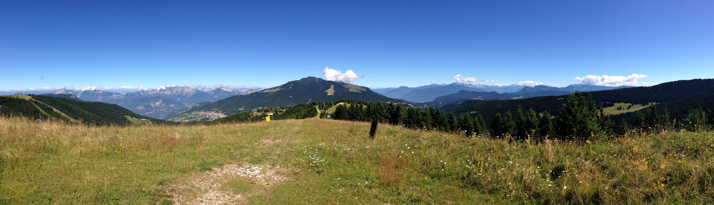 Panoramica NW – NE dal Sommo Alto. Da sinistra (in basso) Folgaria, sullo sfondo le Dolomiti del Brenta, al centro il Monte Cornetto, dietro il Becco di Filadonna (nascosto dalla nuvola) in basso il dorso in cemento del Forte Sommo Alto, a destra l’Altopiano di Lavarone, la zona di Passo Vezzena con lo Spitz Verle e sul bordo destro, l’orlo nord orientale dell’Altopiano di Asiago
