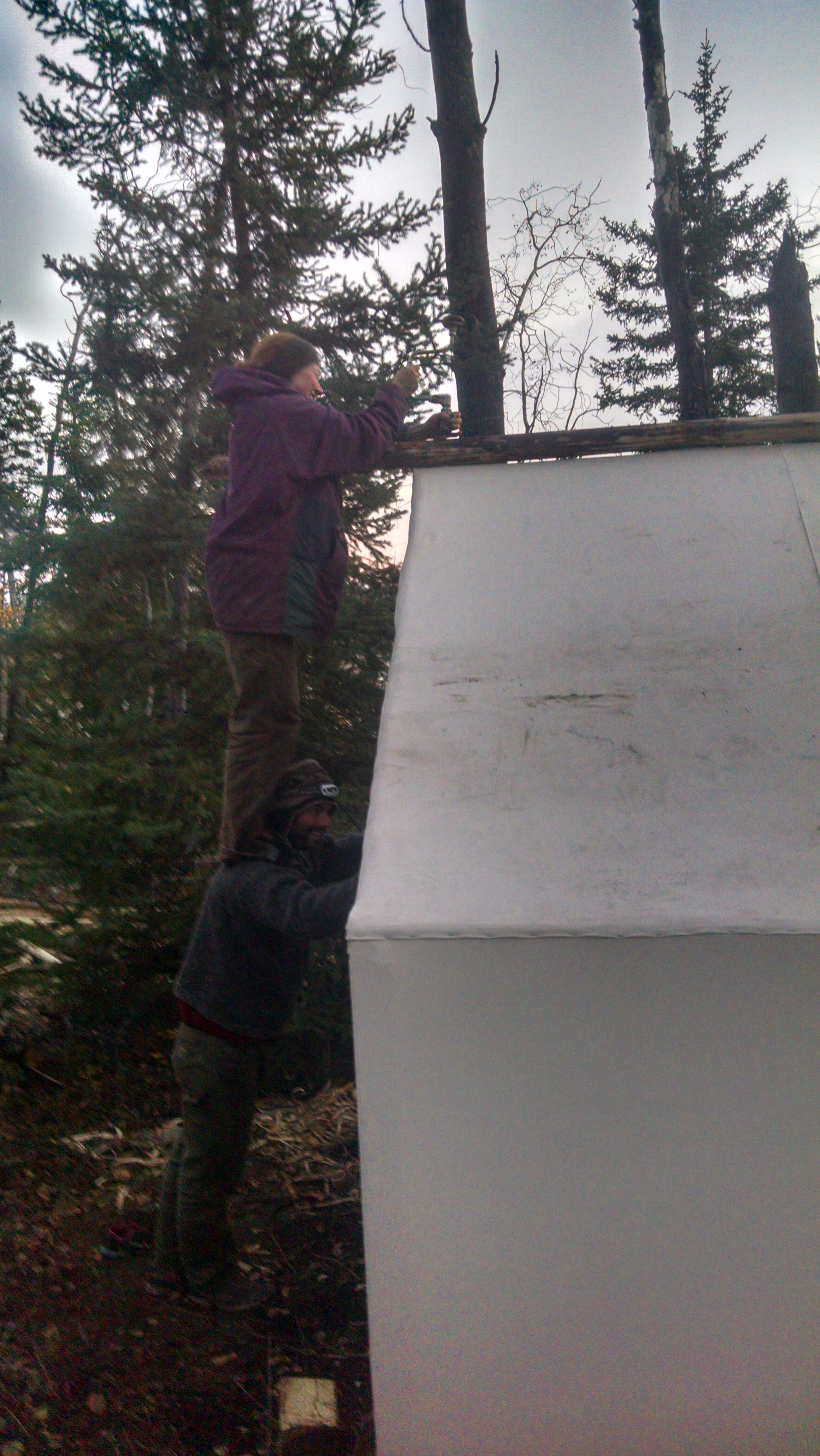 David the "Human Ladder"for Jenna so she can reach the peak to lag bolt the second ridge pole in place.