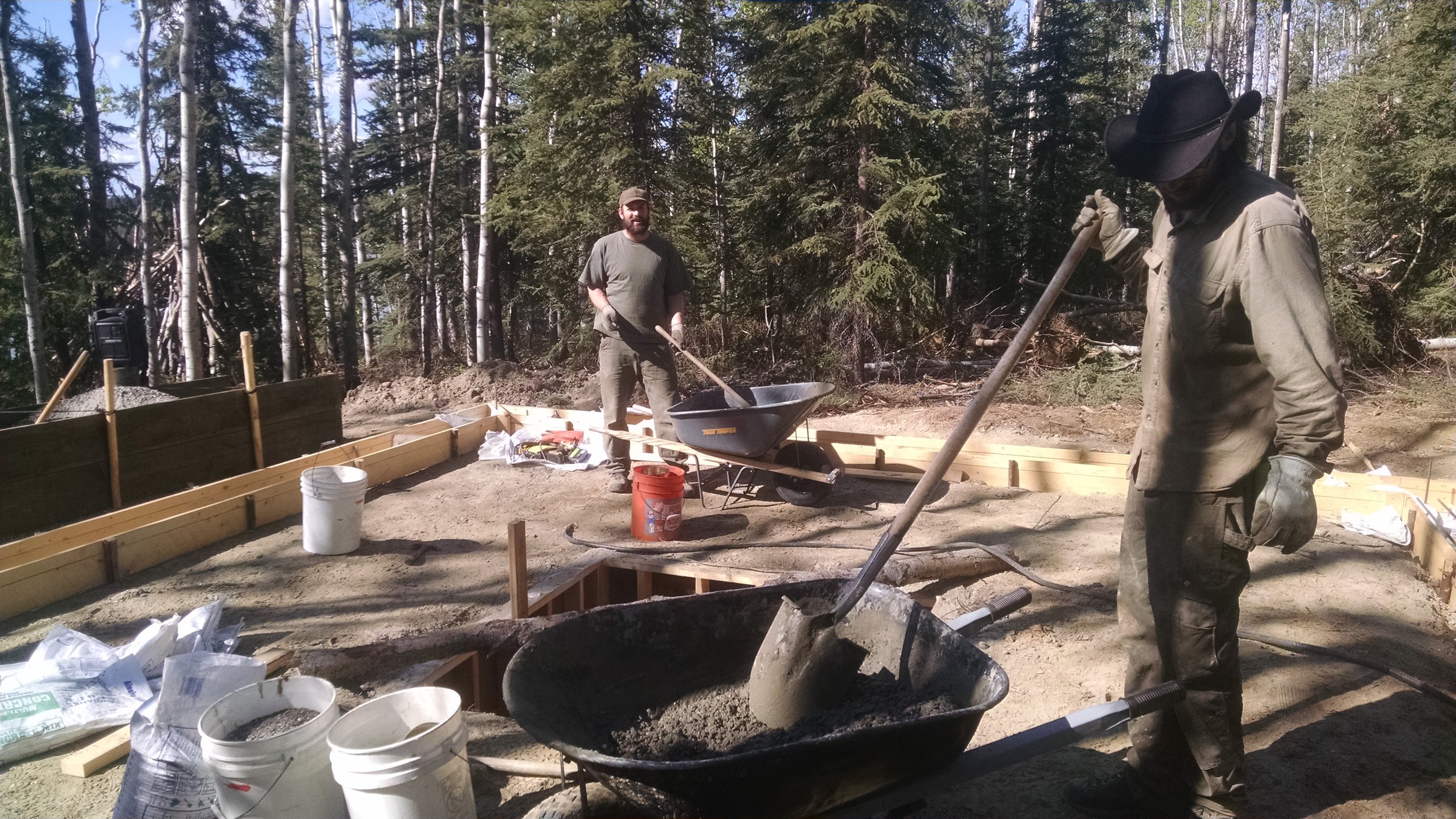 David and Jeff mix loads of concrete in wheelbarrow.