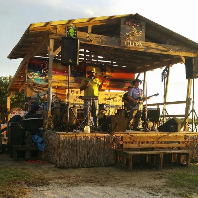 Anthony “Packrat” Thompson and Robert “Lightning Boy”Thomas(aka Top), are founding members of the 4 piece swamp blues band Smokehouse which formed in 1989 in New Smyrna Beach, Fl. Specializing in Florida Swamp Blues, they are powered by the songwriting, storytelling, lead vocals, harmonica, guitar and percussion of leader, “ Packrat”. Born in Lake Helen, Florida and raised in New Smyrna Beach, Florida, “Packrat’s” exposure to the blues came at an early age due to his mother Willie B. Spellars interest in the blues greats. Listening to the records of John Lee Hooker, Jimmy Reed and Howlin’ Wolf and hitting the juke joints and roadhouses in South Florida which featured live blues entertainment, made this music just part of everyday life. But the music of Sonny Boy Williamson is what influenced “Packrat” the most as a young man and sent him in the direction of being a musician. “Packrat” began his professional career as a drummer in the south Florida area in the 70’s where he and Robert Thomas met as members of a local soul band. But “Packrat” soon gave up the drums in favor of the harmonica and years later it was a common interest in roots blues music that brought he and Robert together again when Smokehouse was originally formed in the fall of 1989. Then in ‘95 the name changed to “Packrat’s Smokehouse” and to this day the group is known across the world for its music- Florida Swamp Blues(by Men of the Swamp). Robert Thomas-vocals and guitar. A native of New Smyrna Beach, Florida, Robert has played the Florida club circuit since 1973. As guitarist-vocalist for the popular Central Florida band, “The Payne Brothers Band”, his first musical efforts were in the southern rock tradition. A collector of vintage blues records, his interest in traditional South-Eastern blues grew along with his desire to play in this style. In the spring of 1987 he formed “Town Crier” and recorded several sides for King Snake Records featuring performances by Kenny Neal and Lucky Peterson of Alligator Records. His association with King Snake Records led to an introduction to legendary Lazy Lester and participation in Lester’s 1988 tour as his guitarist and opening act. Robert can be heard on the Alligator release of Lazy Lester’s “Harp and Soul”. In 1989, Robert toured the East Coast blues club circuit with the Florida blues quartet “Blue House”, which frequently featured the legendary Noble “Thin Man” Watts on saxophone. Now with Packrat’s Smokehouse, he continues to serve up Florida Swamp Blues. Aaron “Pop” Watson- drums, vocals. Aaron, known to most as “Ba-Bro”, began playing playing drums as a youngster in his hometown, Daytona Beach, Florida and joined SMOKEHOUSE in 1993. At the age of 15 he began playing the nightclub circuit with his band director, Gideon Pettway. As a teenager, he also played in bands for high school proms both in and out of town. Deemed the best drummer in the area and the teacher of many locals, including John Livingston, Lorenzo Laws, Leroy “Bo Pete” Robinson, Robert Popwell, The Johnson Brothers of Deland, Florida and son Aaron L. Aaron’s professional career can be traced playing in the officer’s club while in the Army to “drumming” for recording greats, Rufus Thomas, Joe Simon, Joe Davis’ revival group, Wilbur Harrison, The Drifters, Betty Swann, Arthur Conley, Bill Stewart, Ollie Woodson(The Temptations) and others. Having been a member of The American Federation of Musicians, Aaron has made stage appearances with Gary Puckett and the Union Gap and Martha and the Vandellas to name a few. On the homefront, Aaron played beachside for many years with The Duke Gainous Quartet, Lawrence “Bird” Burdine, Lindsay Morris and The Universals and several other local jazz and pop bands. Kenny “The Wizard” Sly-bass guitar and vocals. Born in New York City, NY in 1961. Kenny began playing guitar at the age of 9 but switched to trumpet after his older brother broke his electric guitar. Soon, Kenny started playing trumpet in middle and high school band but saw a Live Funk group playing which caused him to pick up the bass in 1976. His influences range from the blues to funk heavy metal and even Latin and reggae. Kenny got his professional start with music playing with bands on military bases on the island of Puerto Rico. After years of playing in the Daytona area, in 1995 he joined SMOKEHOUSE as the newest member and has been with the band ever since. Kings of the Florida Swamp Blues...That’s the music of Packrat’s Smokehouse! Packrat’s Smokehouse is a national recording artist Florida Swamp Blues band out of New Smyrna Beach, Florida. The band was created by Anthony “Packrat” Thompson in 1989. The four members all knew each other from other bands and being natives(except Kenny moved to this area in the late 80s). The band had a song on the Aaron Spelling TV production “Savannah” on WB network in ‘96 and their music was included in the soundtrack for the feature film, “The Road to Canyon Lake” (‘04). Anthony “Packrat” Thompson is a raw, greasy harmonica player, evoking the swamp sounds of Baton Rouge that has spread and taken root in the steamy Florida lowlands. His voice is reminiscent of Little Walter and Howlin’ Wolf. The lowdown guitar of Robert Thomas, who is equally impressive, can spit out fiery solos and muscular riffs reworking deep, swampy grooves of New Orleans and Delta blues, making you think of the pine flatwoods and cypress bottoms of Central Florida. “Packrat” and Robert were both raised in New Smyrna Beach, Florida. Although they have shared bandstands since the 70s, it was until 1988 that they began to explore their common roots and their love of the Blues. Smokehouse recorded four groundbreaking CDs in the 90s that defined the genre of Florida Swamp Blues. Living Blues magazine said of their third release, Cadillac in the Swamp: ”The year 1995 was a great one for blues recording, but this irrepressible set of updated swamp blues earns this reviewer’s vote as the best of the lot”. Countless other stellar reviews of the band’s recordings and live performances have been published. After notching thousands of performances together in 35 states, the band shows no signs of slowing down. They are currently working on their much anticipated fifth release titled-”The Men of The Swamp” and continue to maintain a schedule of nightclub and festival engagements including an appearance in spring 2018 at The Lillehammer(Norway) Blues Festival. They have opened for acts such as: “Third Eye Blind”, “Jim Belushi Blues Brothers Revue”, “Carrot Top”, “The Del Vikings”, “The Fabulous Thunderbirds”, “Canned Heat”, “Elvin Bishop”, “Grinderswitch”, Koko Taylor among many others. Most importantly, the band members love what they are doing and have grown to be true brothers in the Blues, which shows in their sound, style and presence. website-www.packratssmokehouse.com(high resolution photos), other website(high resolution photos)www.packratssmokehousemusic.com www.amazon.com/Cadillac-Swamp-Smokehouse/dpB000005A70 www.youtube.com/watch?v=sjPEuDtocOQ
