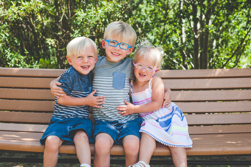 three smiling children. three siblings. young siblings. family photos in the summer.