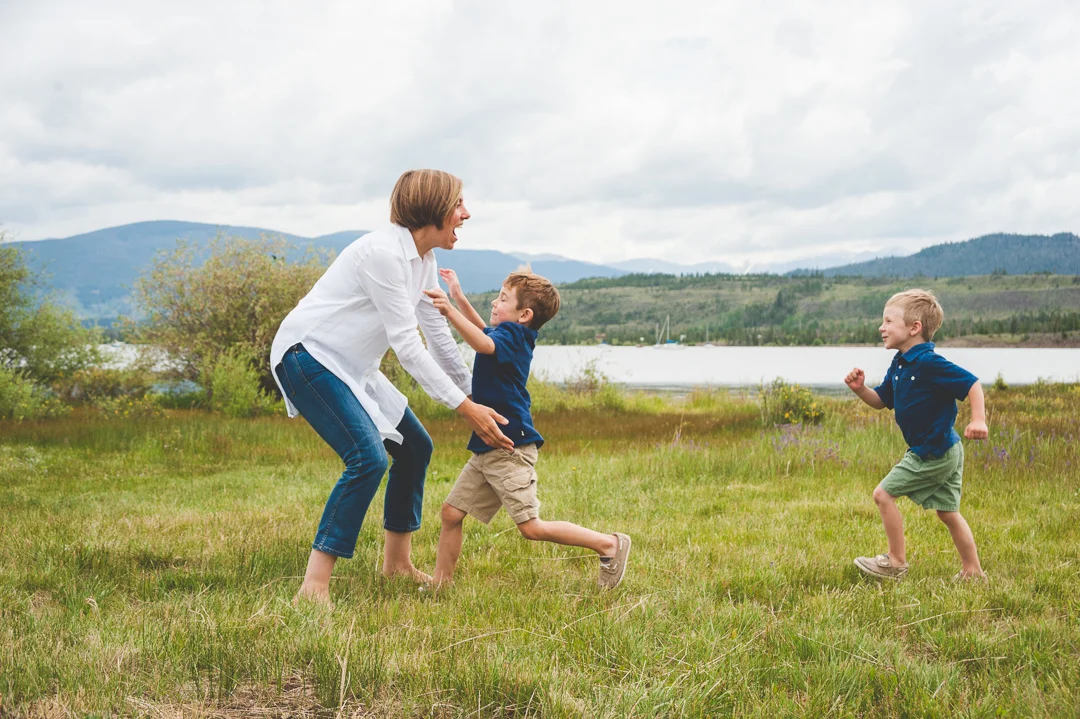 Two young brothers run into their mother's arms for a giant hug during their family photo session by Lake Dillon in Colorado.