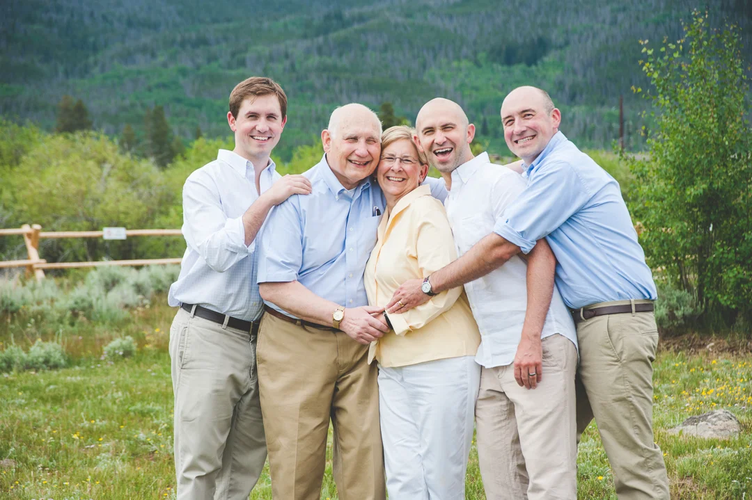 Mom, Dad and three grown sons all hug in tight for a sweet, intimate family photo during vacation in the mountains of Colorado.