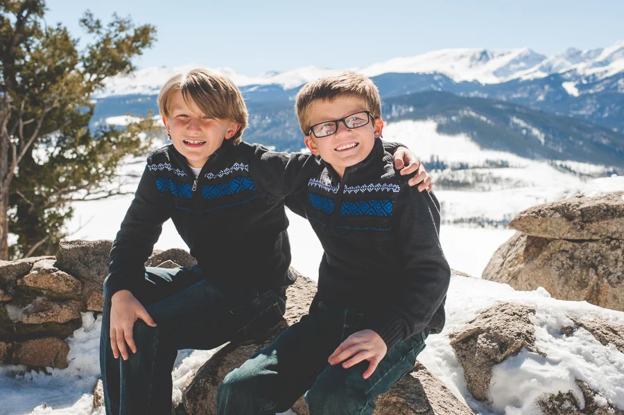 Brothers in matching sweaters (cute!) put arms around one another for a sweet family photo session in the snowy mountains of Breckenridge, Colorado.
