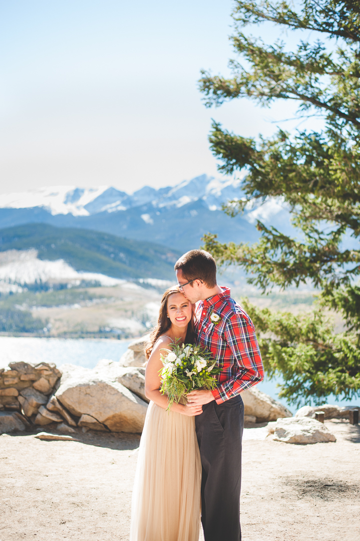 A Colorado elopement at Sapphire Point with snowy, white peaks behind the couple and a warm, autumn sun shining.