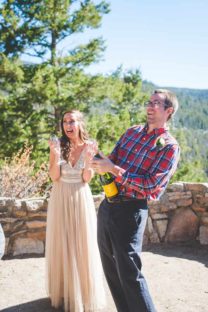 A Colorado groom pops the cork on the champagne after their intimate elopement at Sapphire Point. | Keeping Composure Photography