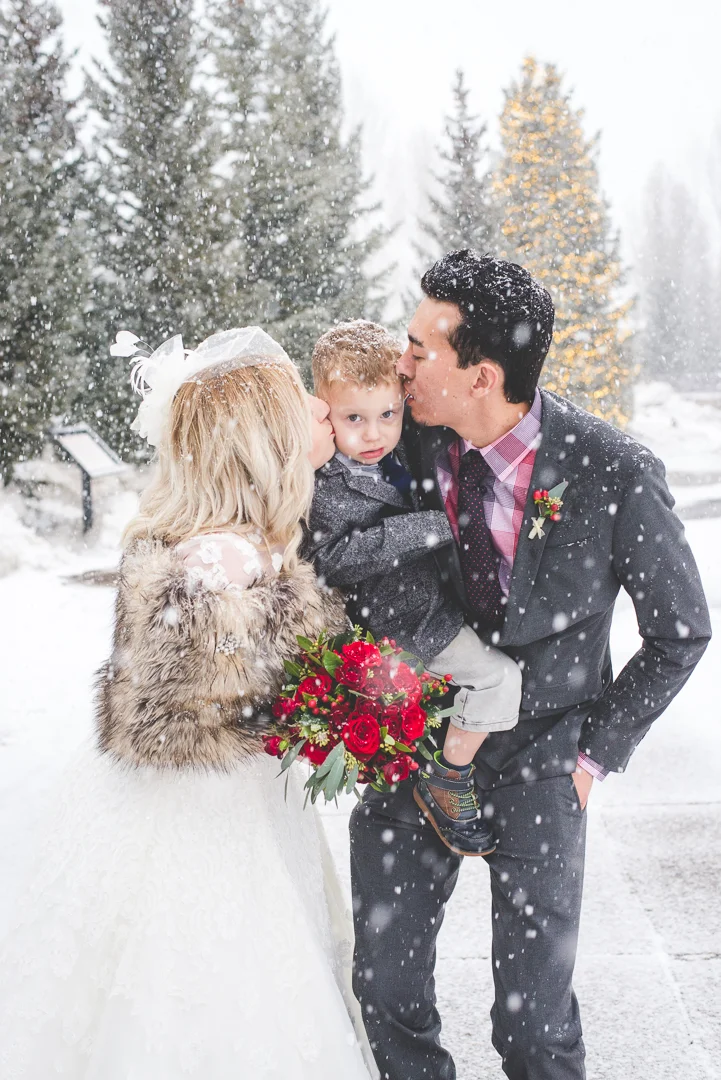Mom and Dad (Bride and Groom) give their son a quick kiss in the snow before continuing with their elopement photos. | Keeping Composure Photography 