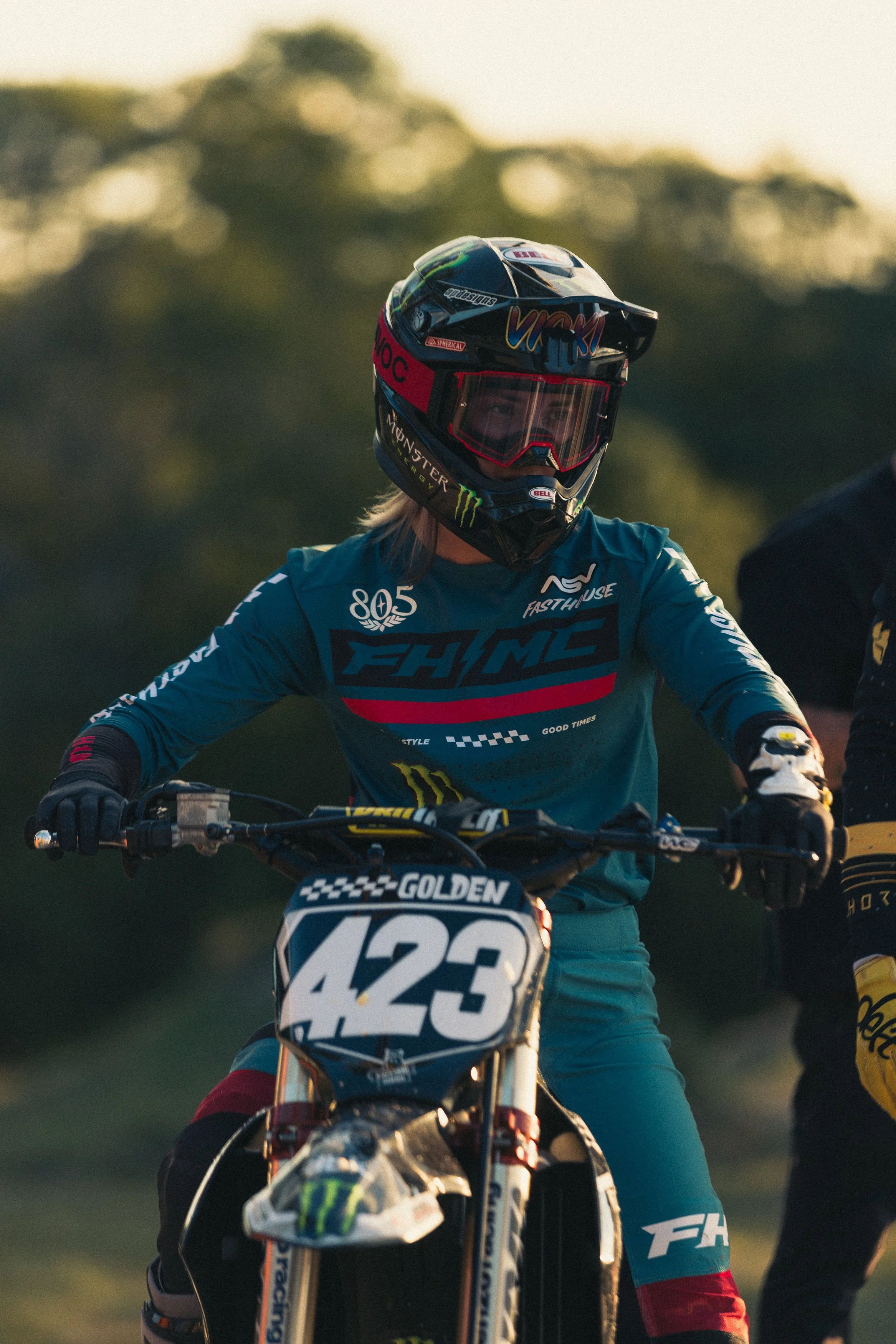 A motocross rider wearing a helmet and racing gear, sitting on a dirt bike with the number 423, outdoors during the daytime.