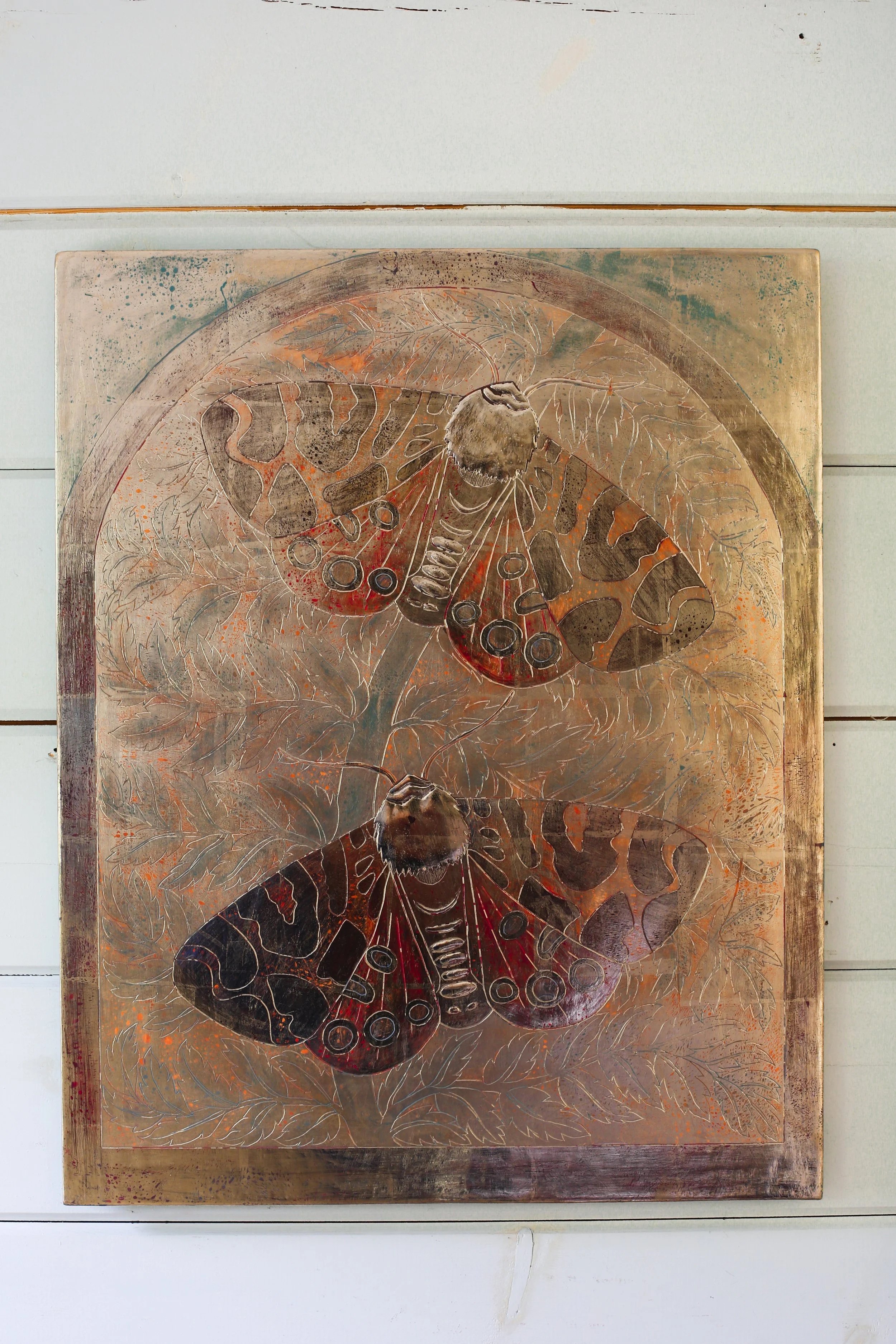 Painting of two moon gold leaf moths with detailed wing patterns, set against a background of foliage, painted on a wooden panel.