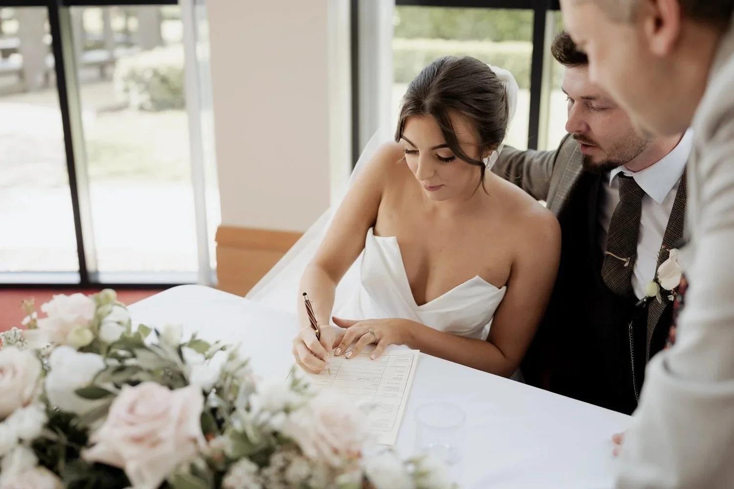 Bride signing marriage schedule with groom looking on after their wedding ceremony in Northern Ireland