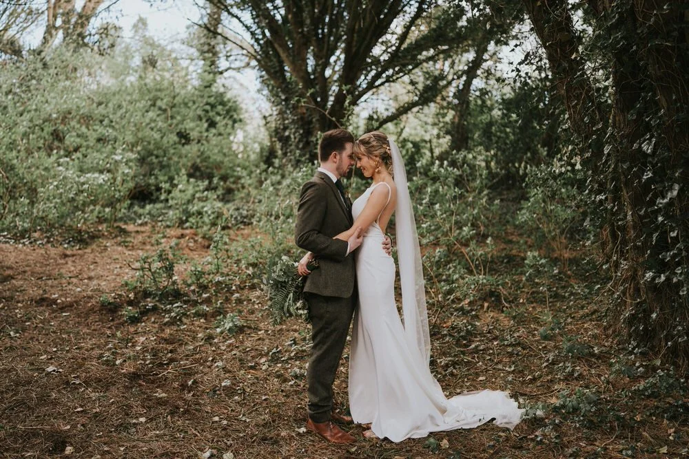 Fiona and Emmet embracing among the trees in the grounds at Orange Tree House