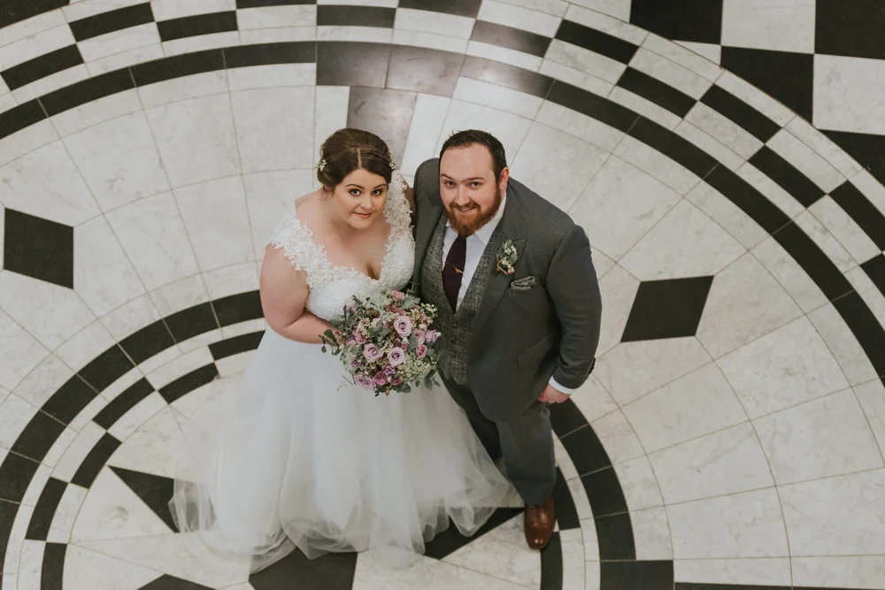 Bride and groom photographed from above on the black and white marble floor of Belfast City Hall