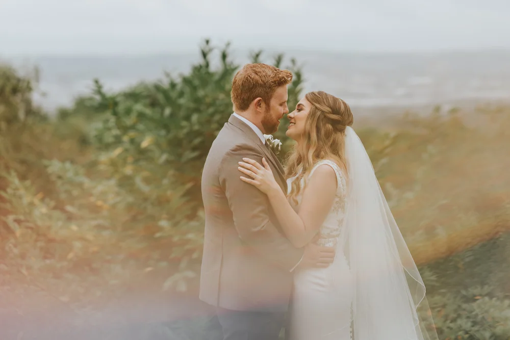 Ciara and Robert embracing in the gardens at Belfast Castle with the lough in the distance