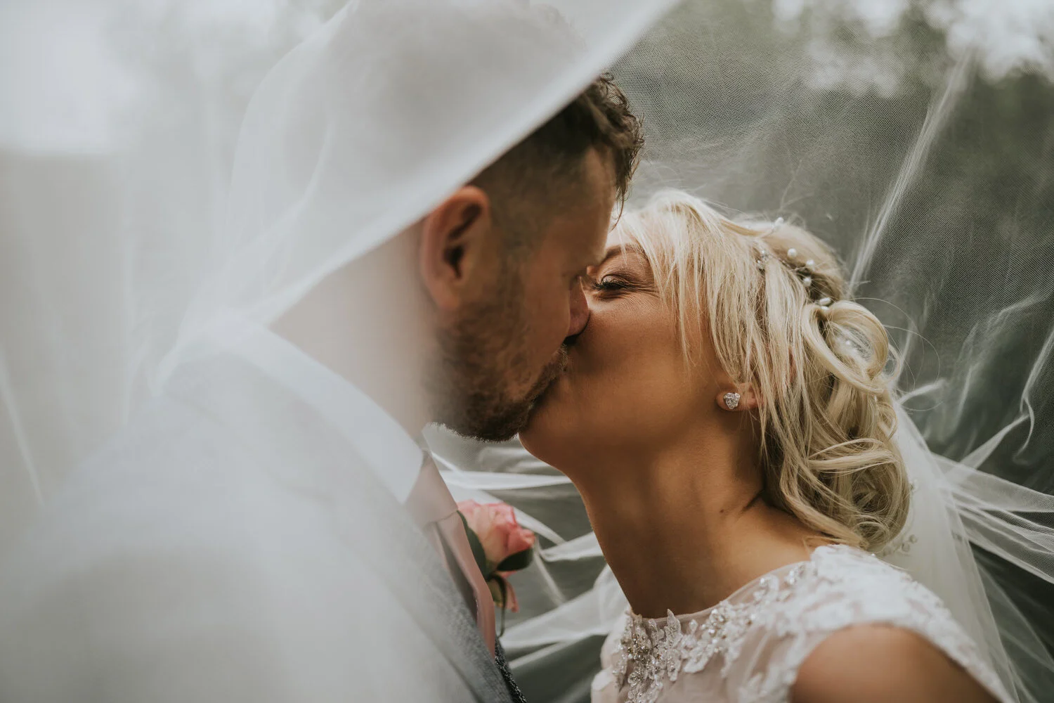 Groom and bride kissing under the bride's veil at Millbrook Lodge
