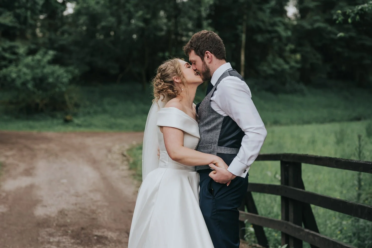 Bride and groom sharing a kiss beside a wooden fence at Glenpark Estate