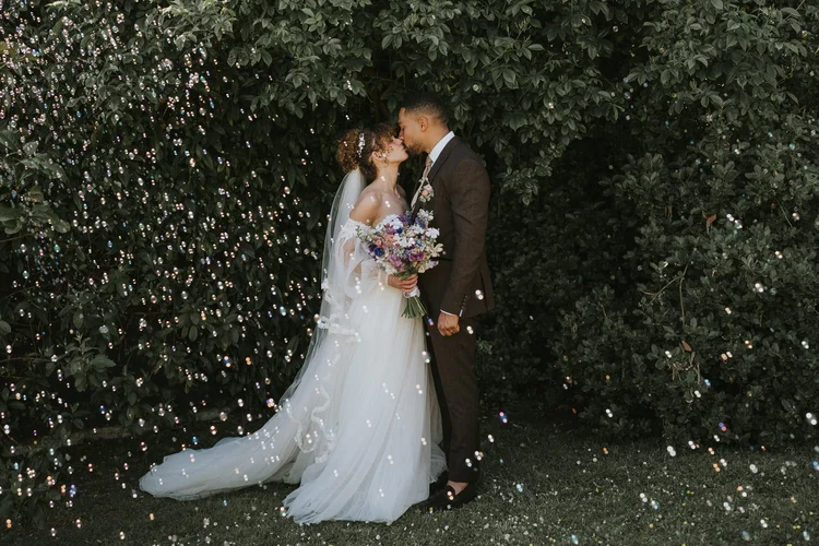 Bride and groom kissing under falling confetti at Lissanoure Castle