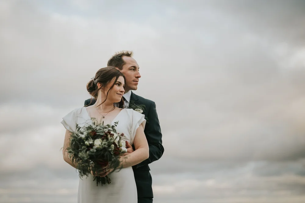 Sarah-Jane and Andrew embracing under a cloudy sky on their winter wedding day at Clandeboye Lodge