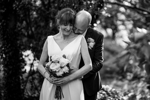 Susan and David in a close embrace in black and white, Susan holding a bouquet of roses
